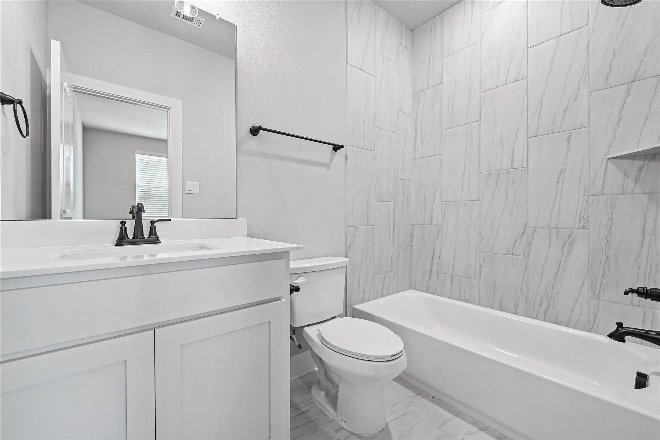 White shaker-style vanity with a single basin sink, white countertop, and matte black fixtures