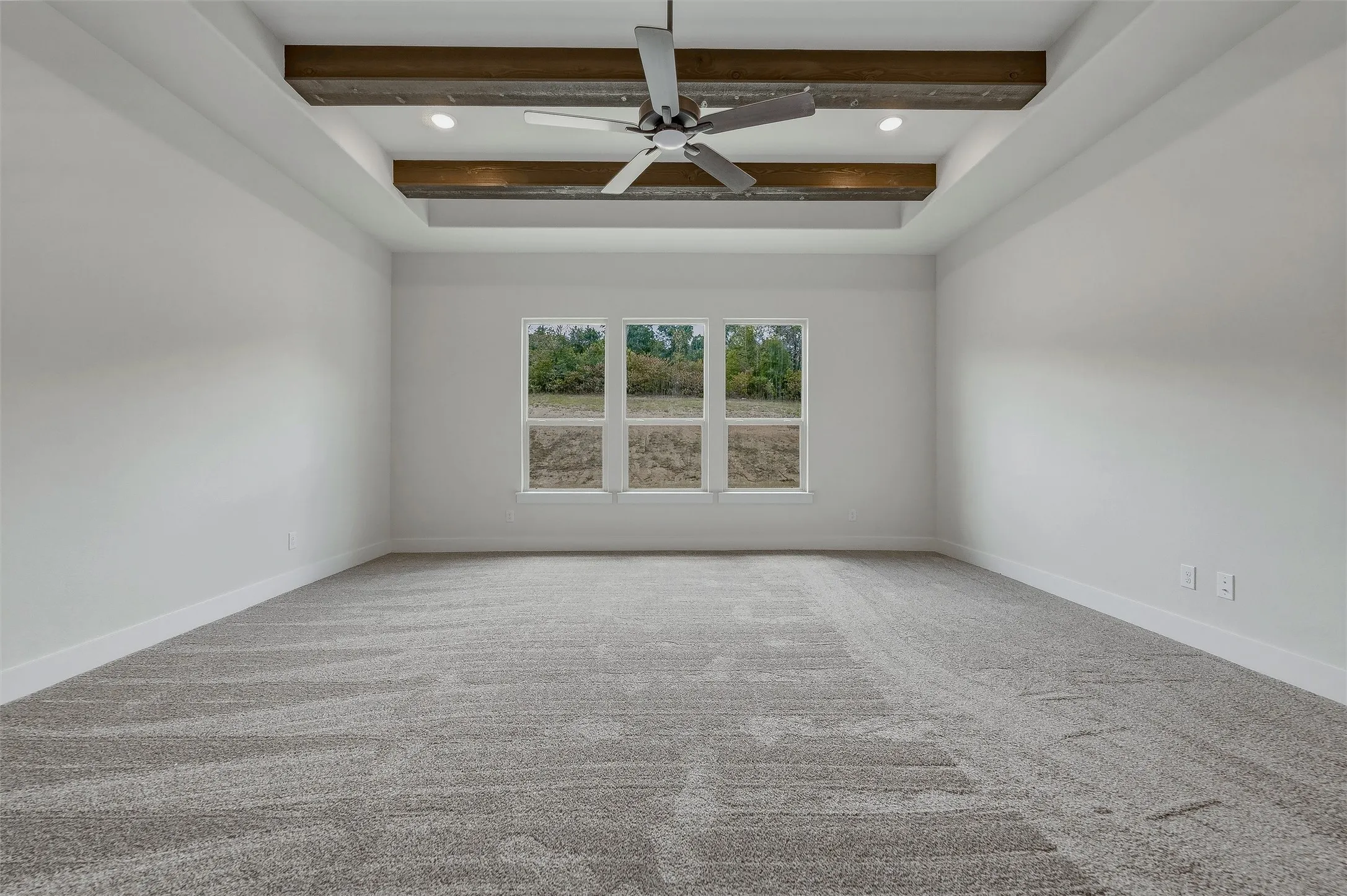 Tray ceiling with wood-finish beams, recessed lighting, and a ceiling fan