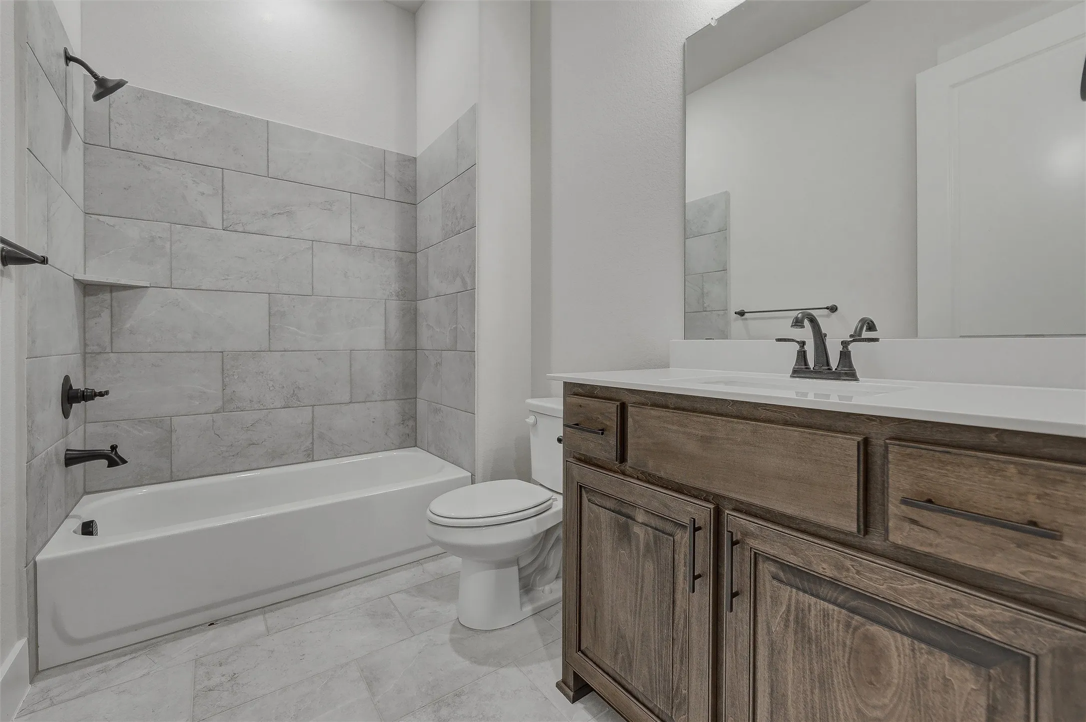 Bathroom featuring a wood-finish vanity with a light-colored countertop, an undermount sink, and a large mirror