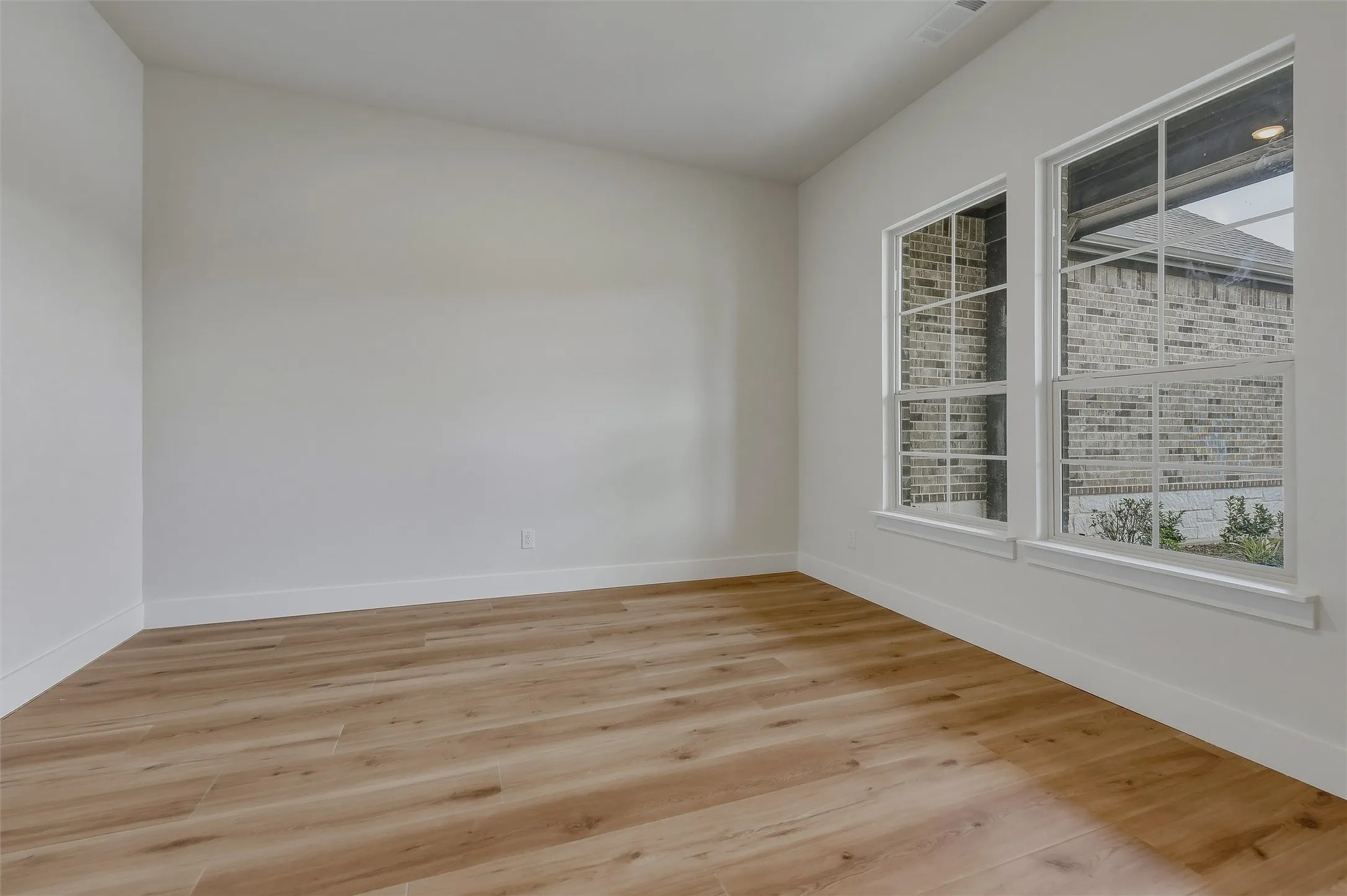 Vaulted ceiling, two transom windows, wood-finish flooring, and white baseboards