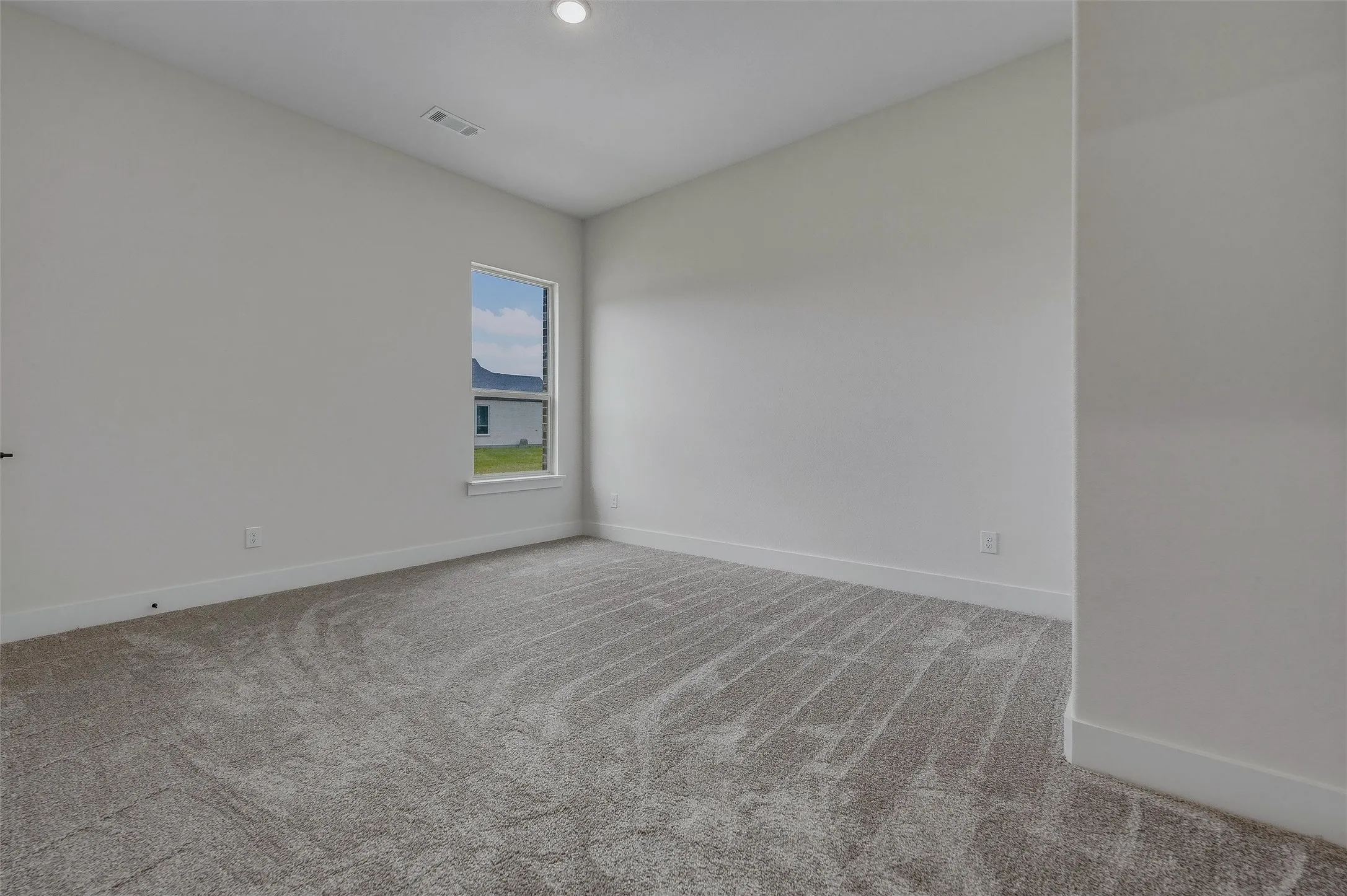 Recessed ceiling light, neutral wall paint, single window, and textured carpeting