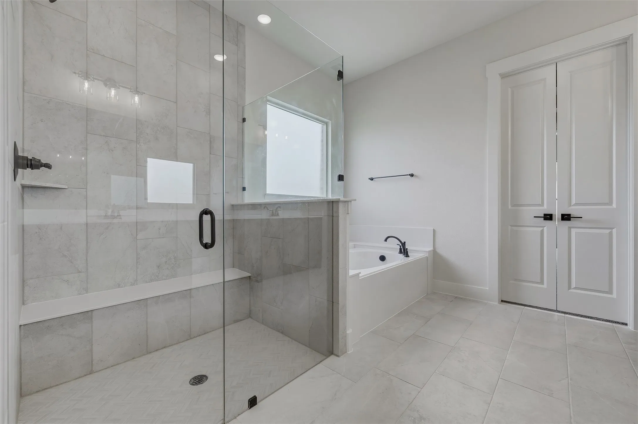 Glass-enclosed shower with a built-in bench, tiled walls, and a recessed ceiling light