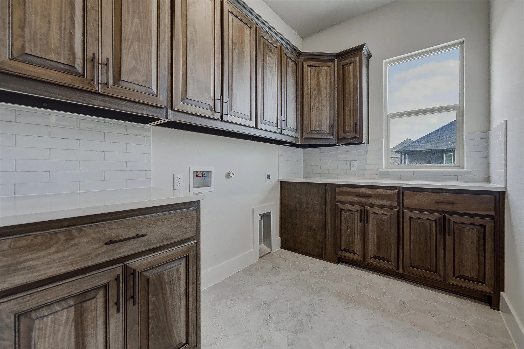 Extensive cabinetry with dark wood finish, light countertops, white subway tile backsplash, and light hexagonal tile flooring