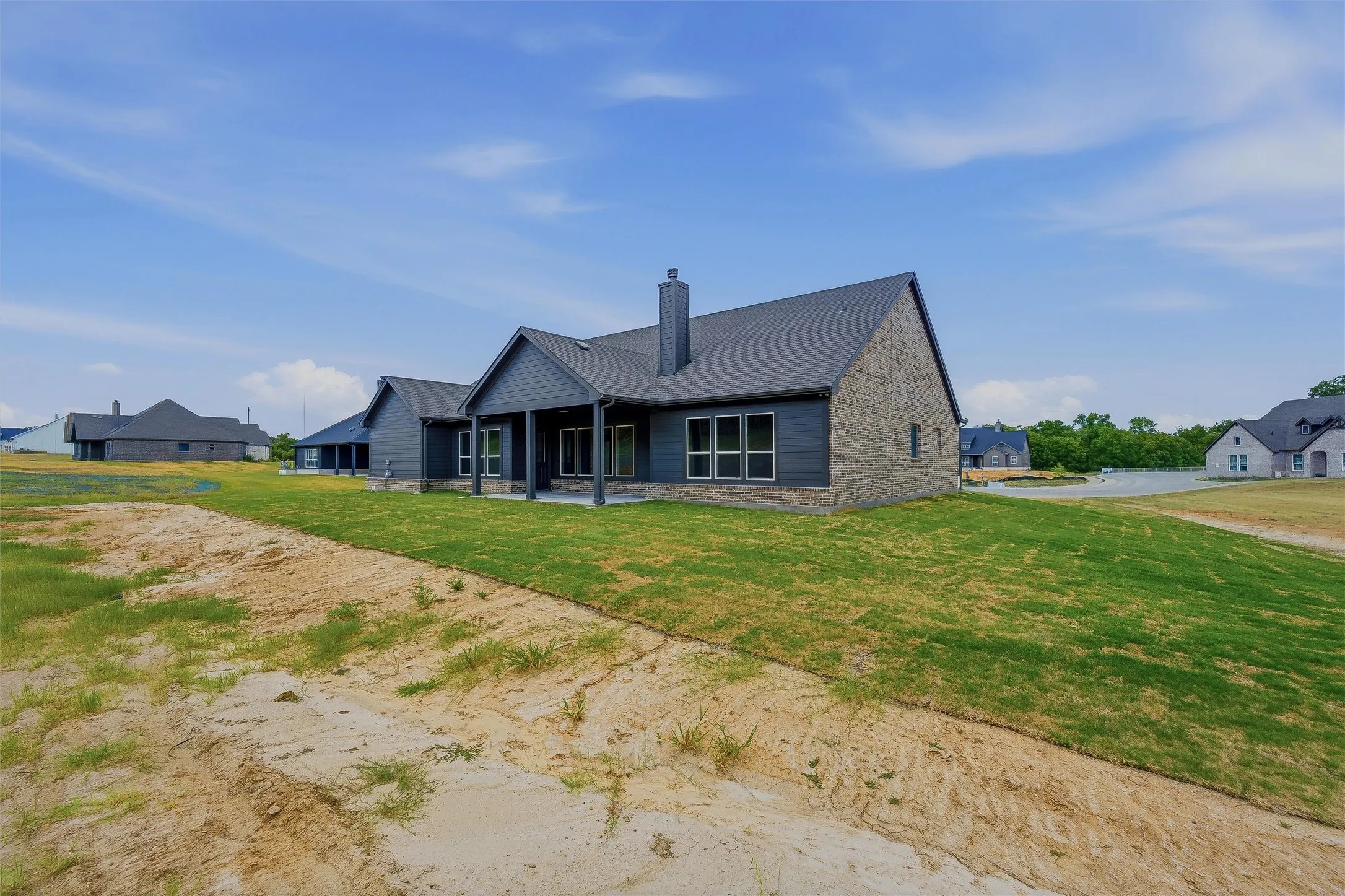 Contemporary exterior with brick and horizontal siding, covered rear patio, multi-pane windows, and a dark shingle roof