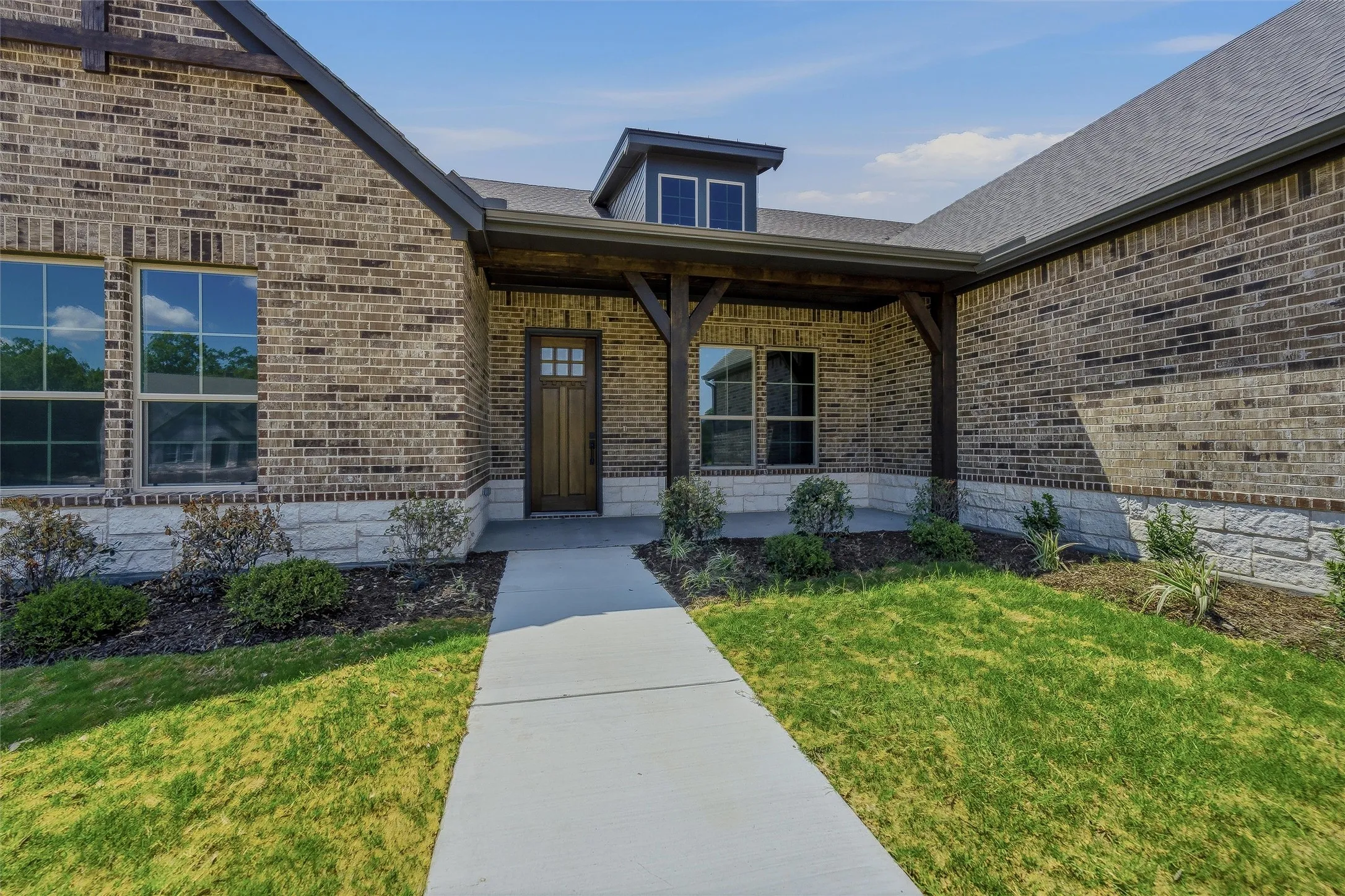 Brick exterior with stone accents, covered entry, and dormer window