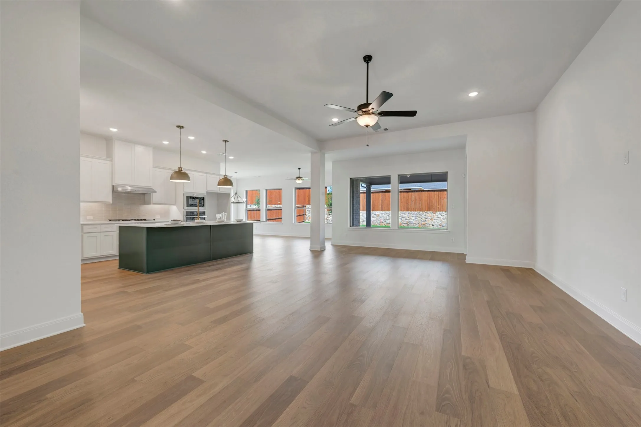 Open-concept living area with wood-finish flooring, recessed lighting, and a ceiling fan