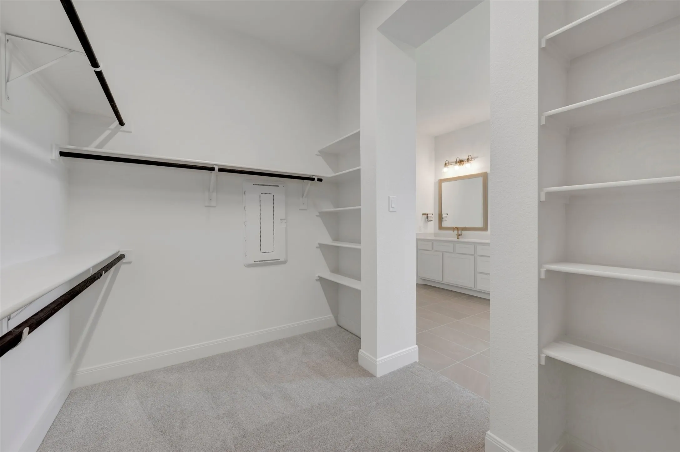 Spacious walk-in closet with carpet flooring, built-in shelving, and hanging rods