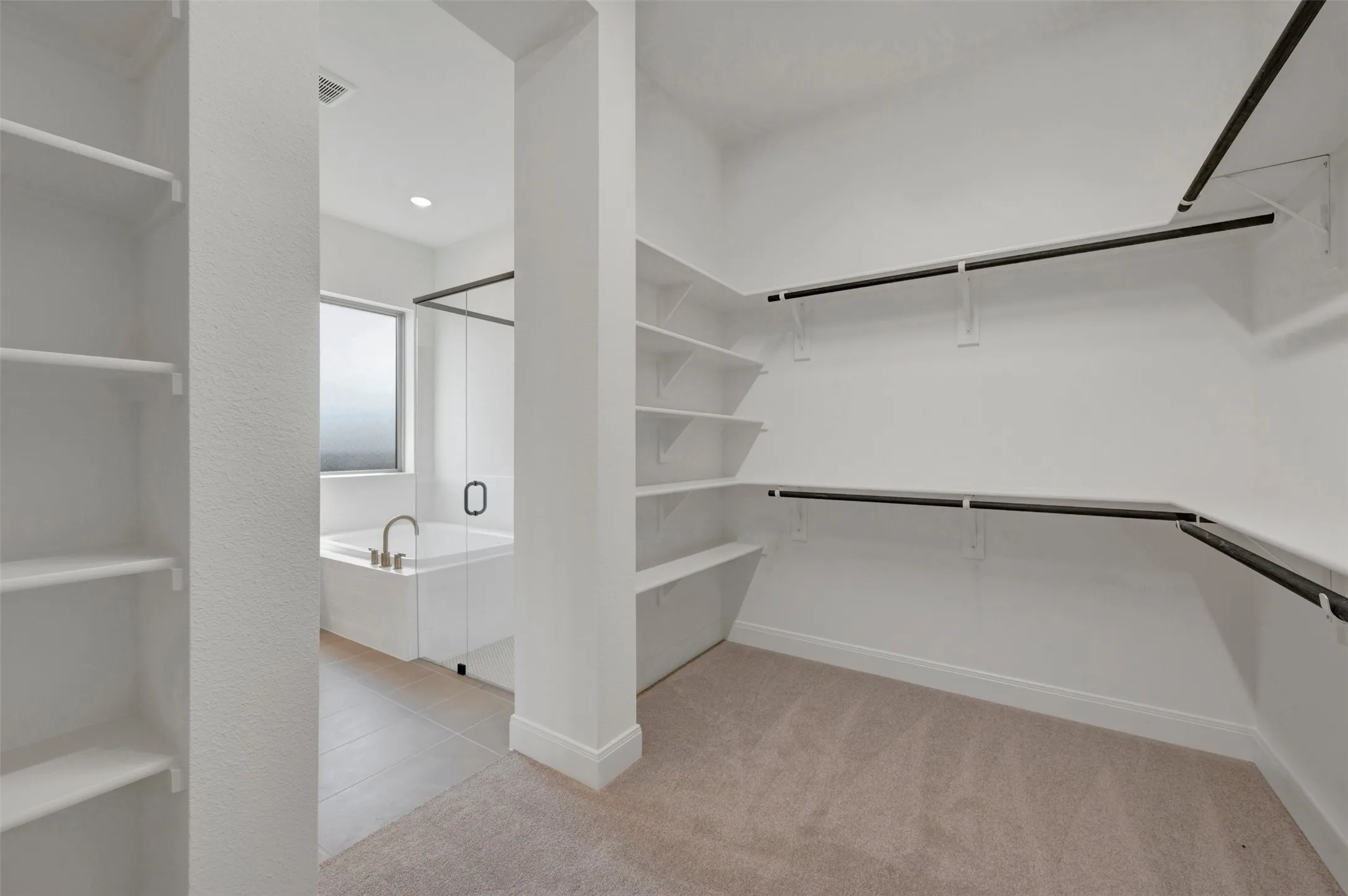 Spacious closet featuring built-in shelving, hanging rods, and neutral carpet