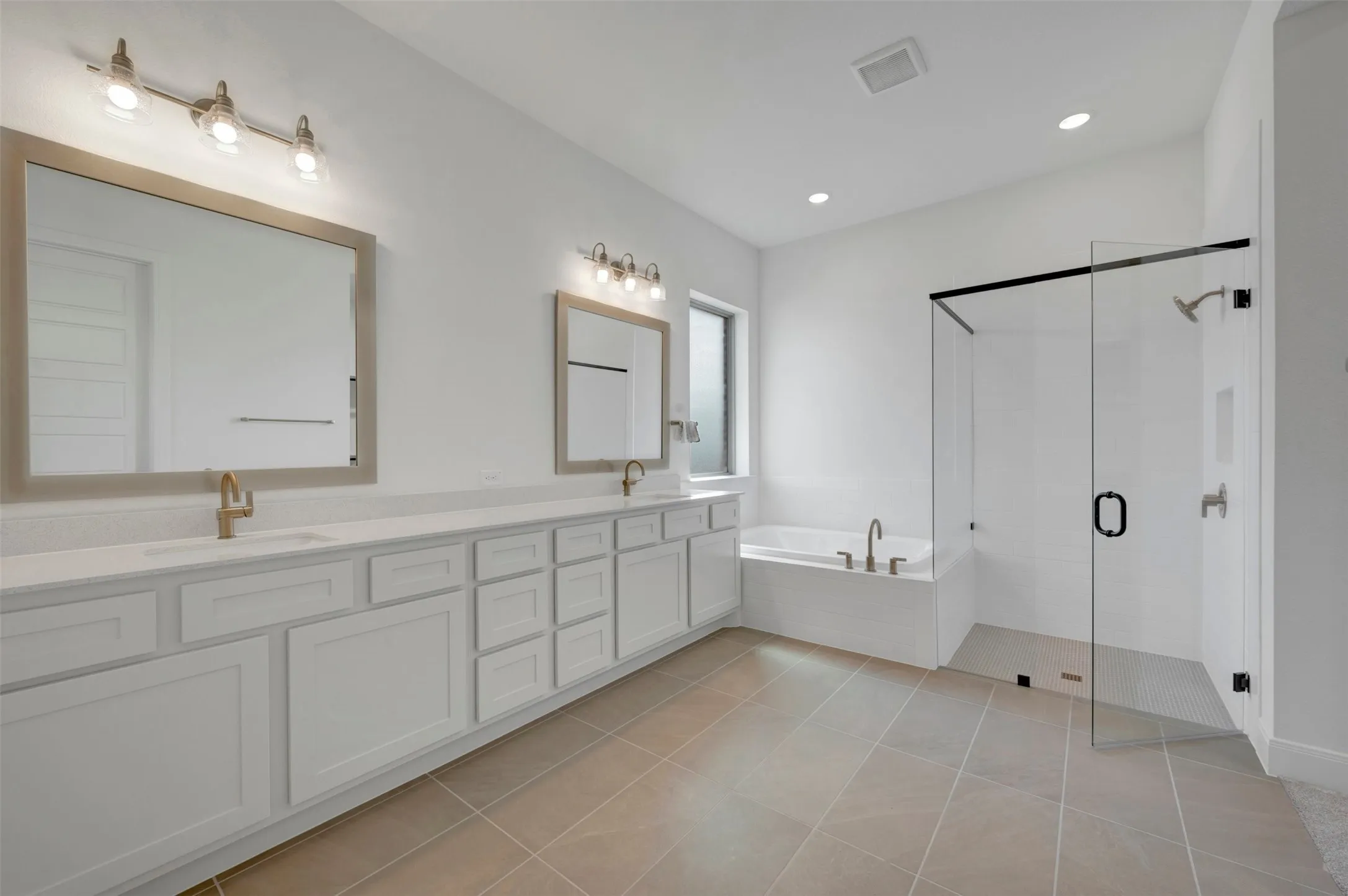 Dual vanity with quartz countertops, white cabinetry, and brushed brass fixtures
