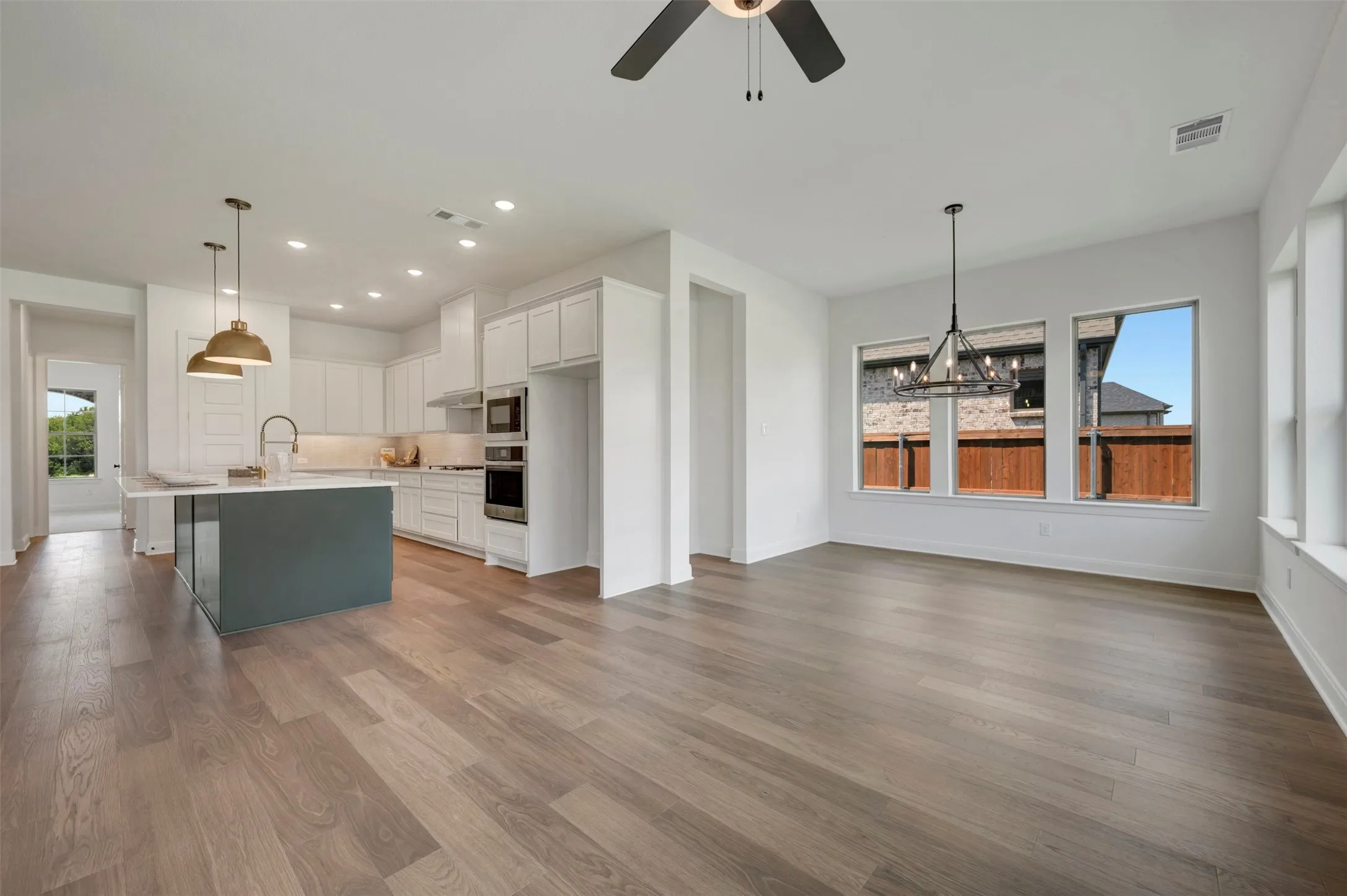 Spacious kitchen featuring an island with pendant lighting, stainless steel appliances, and white cabinetry