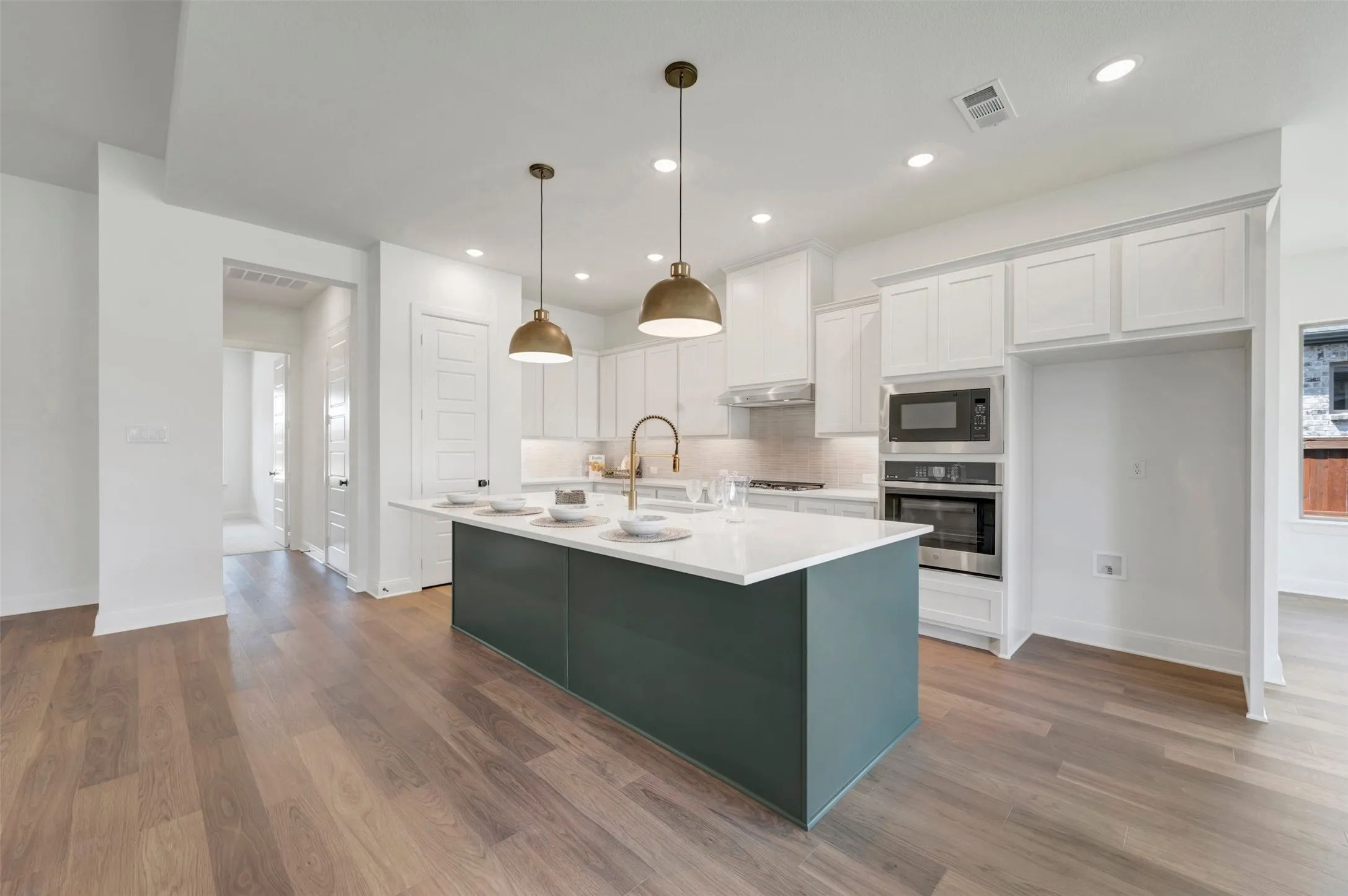 Kitchen featuring a center island, wood-finish flooring, white cabinetry, built-in stainless steel appliances, and recessed lighting