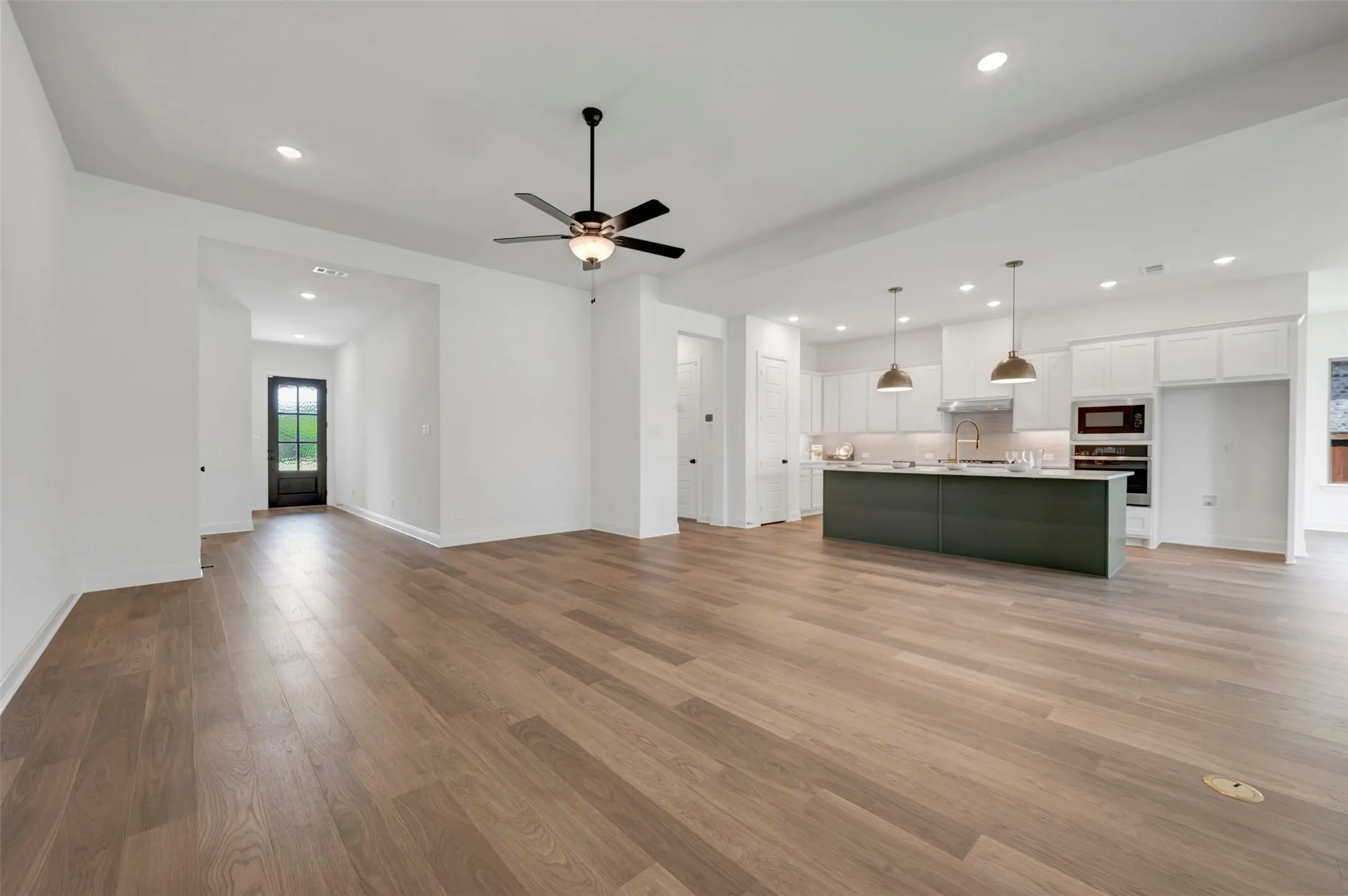 Open-concept living area with wood-finish flooring, a contemporary ceiling fan, and recessed lighting