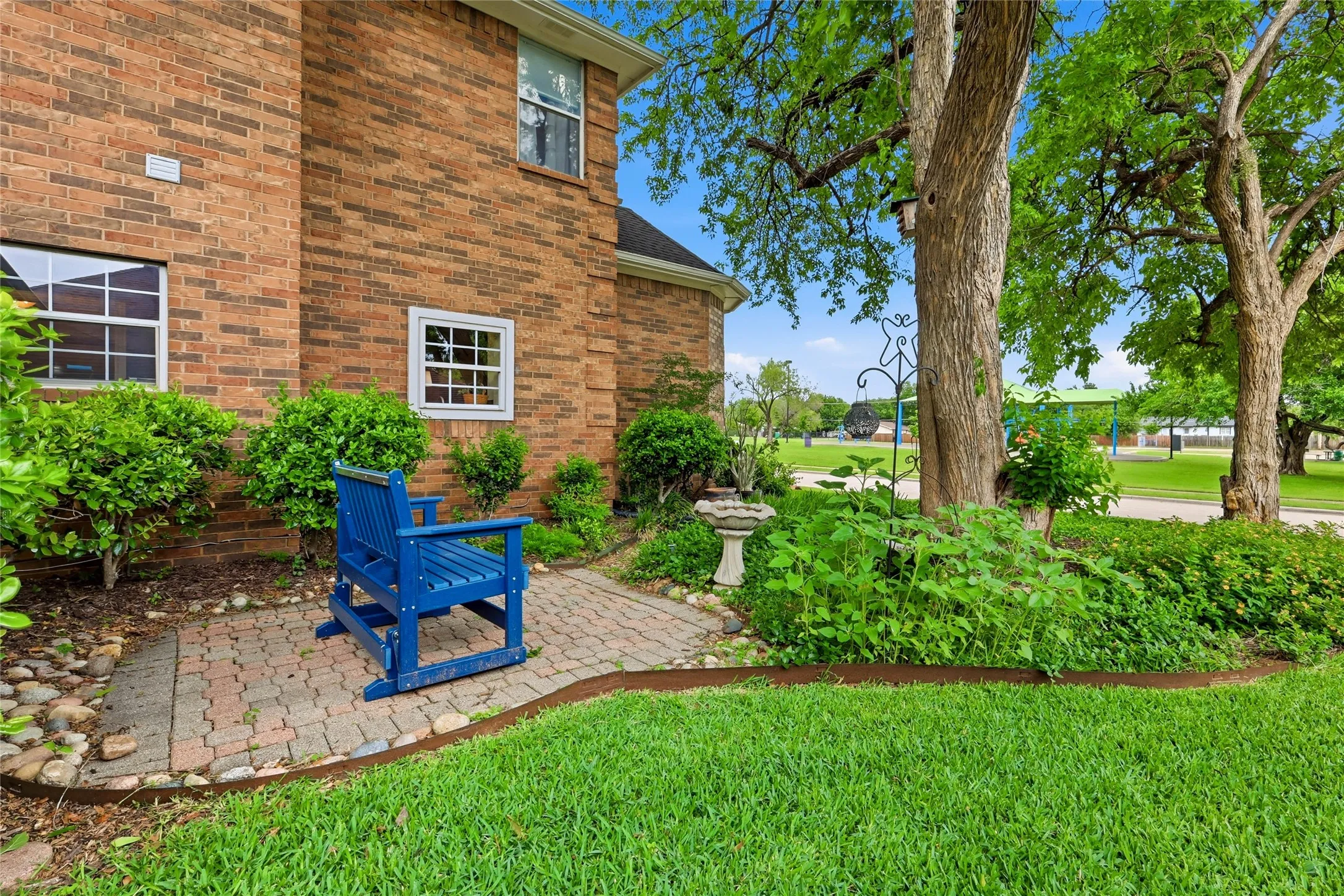 Manicured and landscaped side yard with a view of the park across the street.