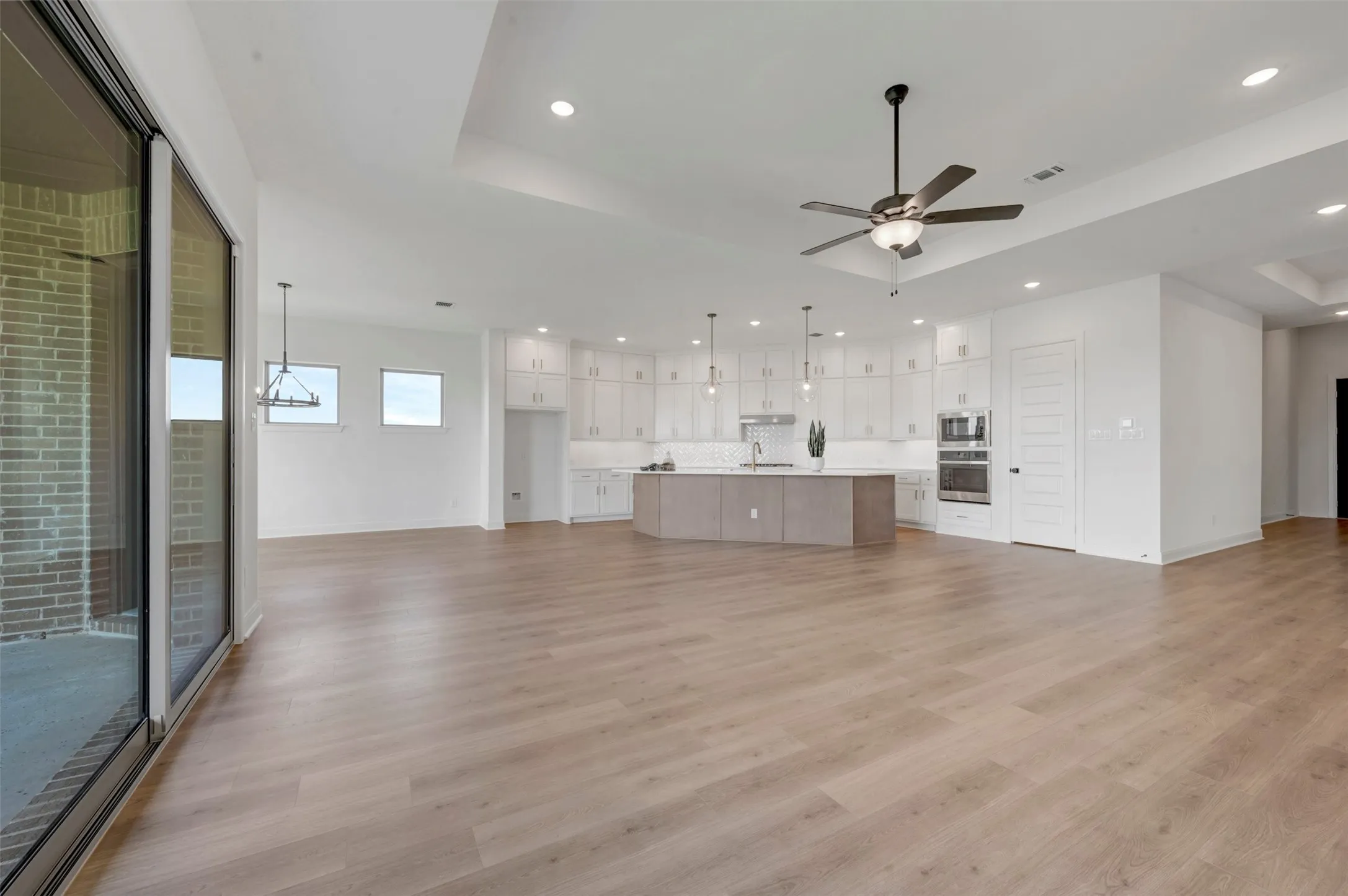 Open-concept living area with wood-finish flooring, a contemporary ceiling fan, and recessed lighting