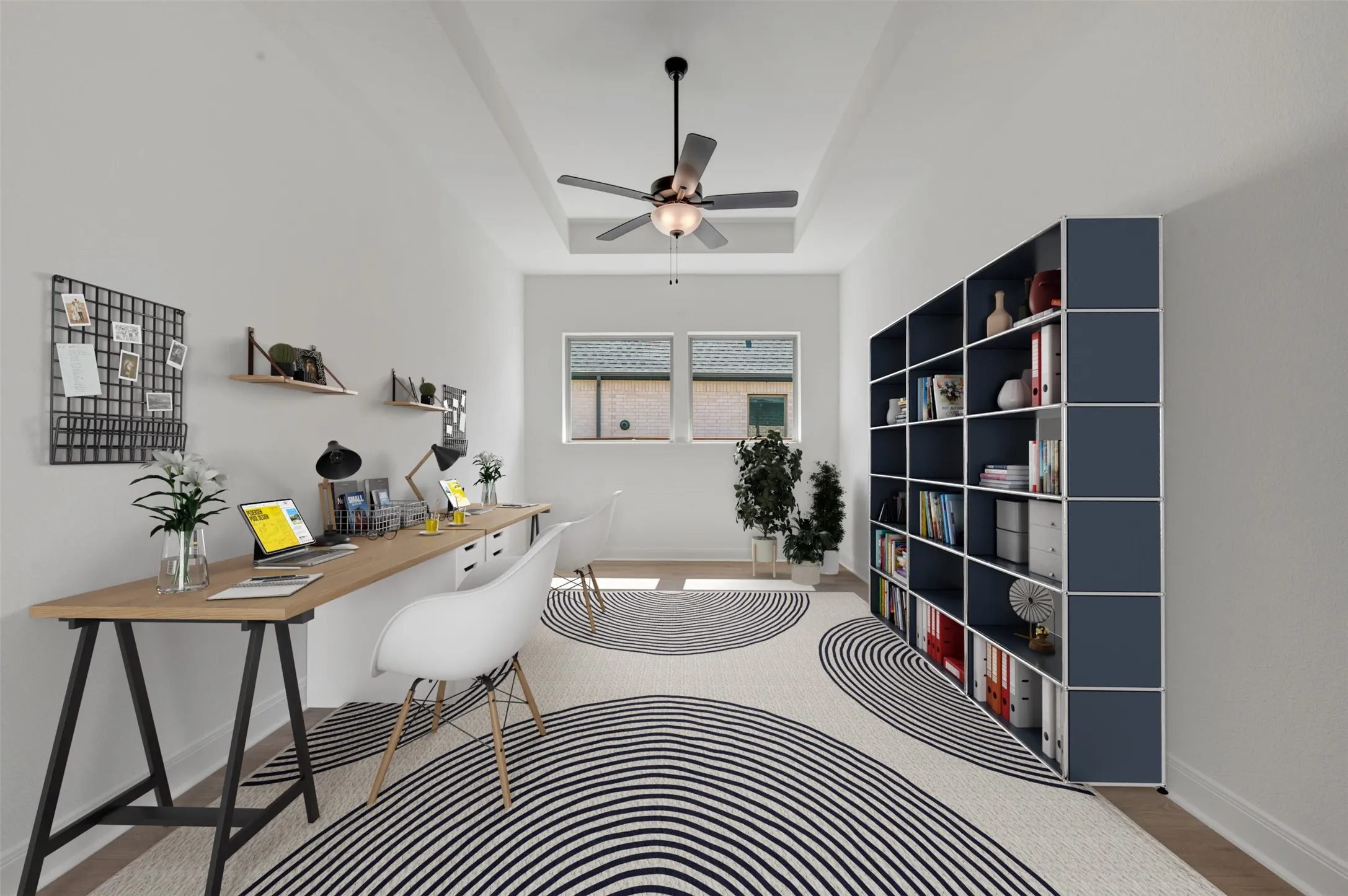 Tray ceiling with a ceiling fan, dual windows, and built-in shelving