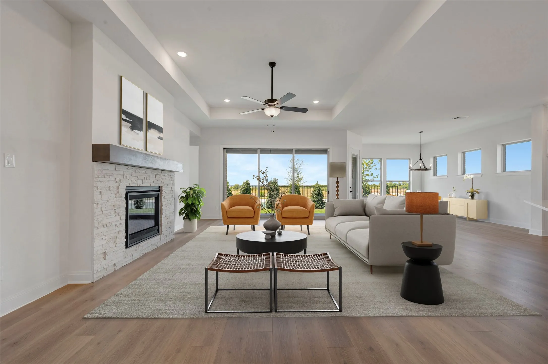 Spacious living area featuring wood-finish flooring, a contemporary fireplace with a stone surround and wood mantel, recessed lighting, and a ceiling fan