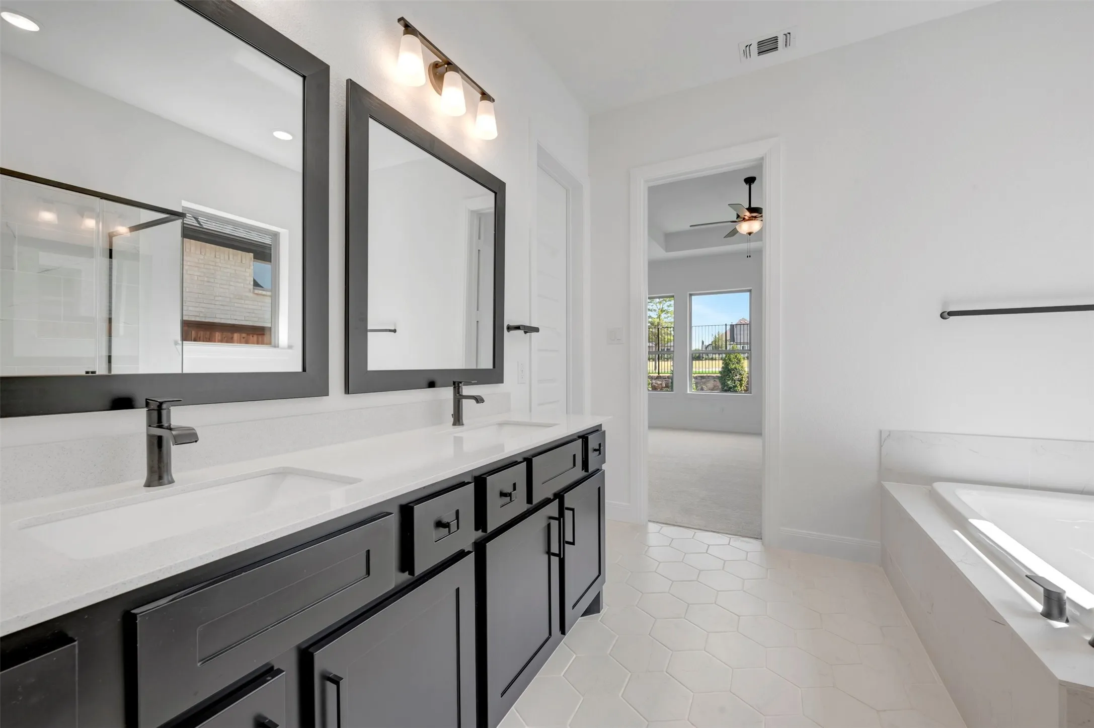 Dual vanity with dark cabinetry, white countertops, and matte black fixtures