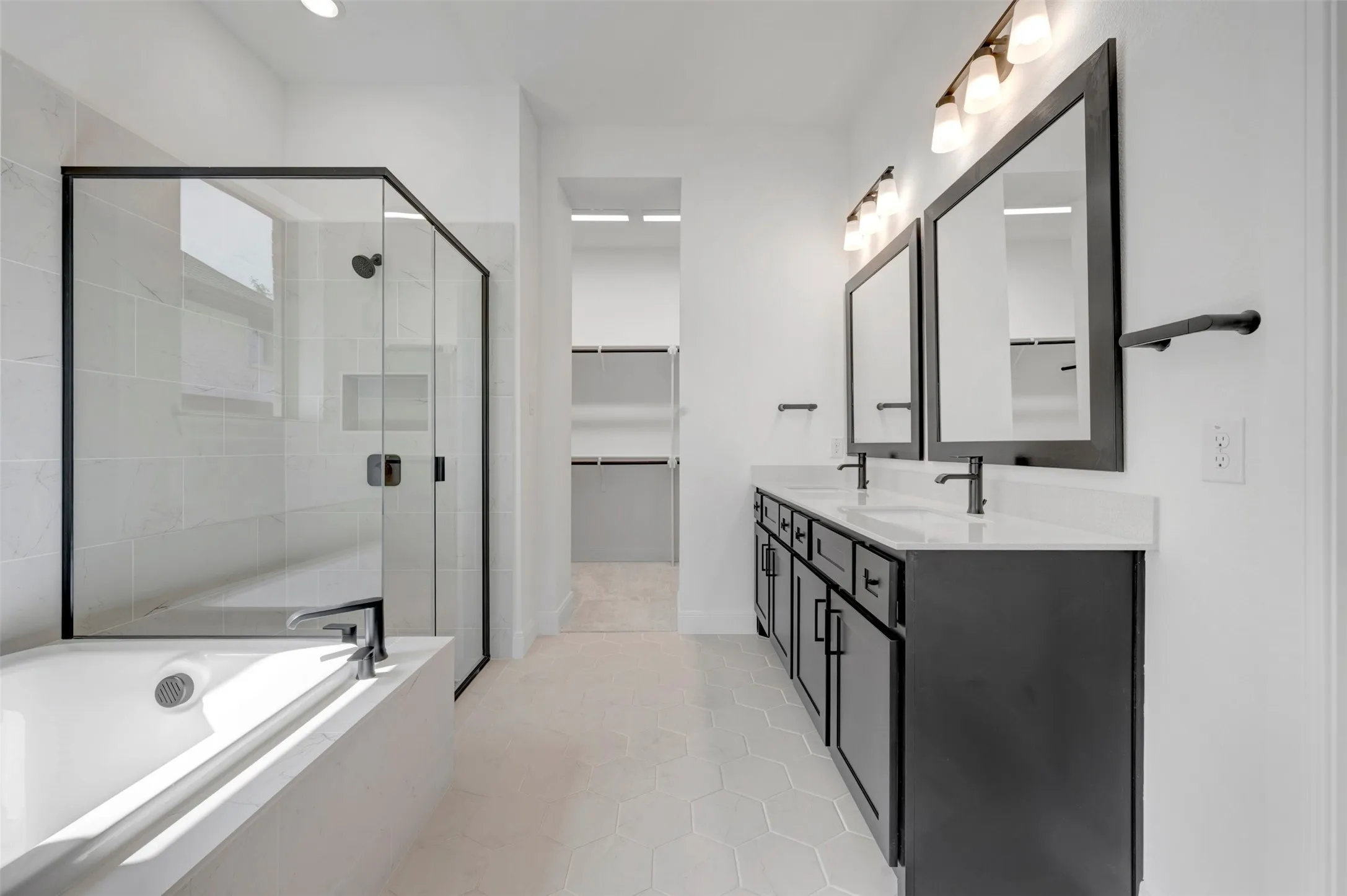 Dual vanity with undermount sinks, an enclosed glass shower, a built-in tub, and hexagon tile flooring