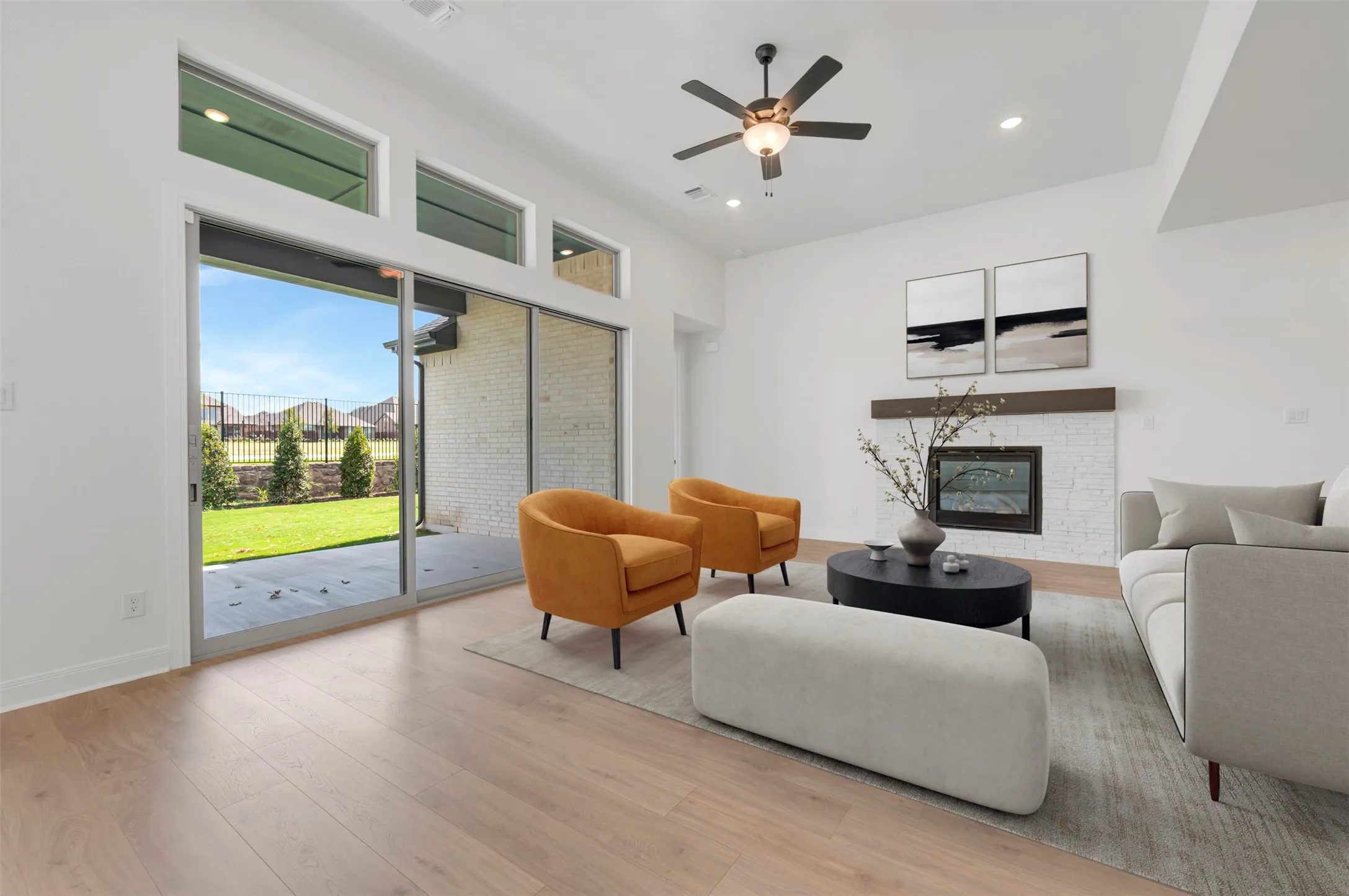 Vaulted ceiling with a ceiling fan, wood-finish flooring, fireplace with a tiled surround and wood mantel, recessed lighting, and large sliding glass doors providing access to an outdoor patio