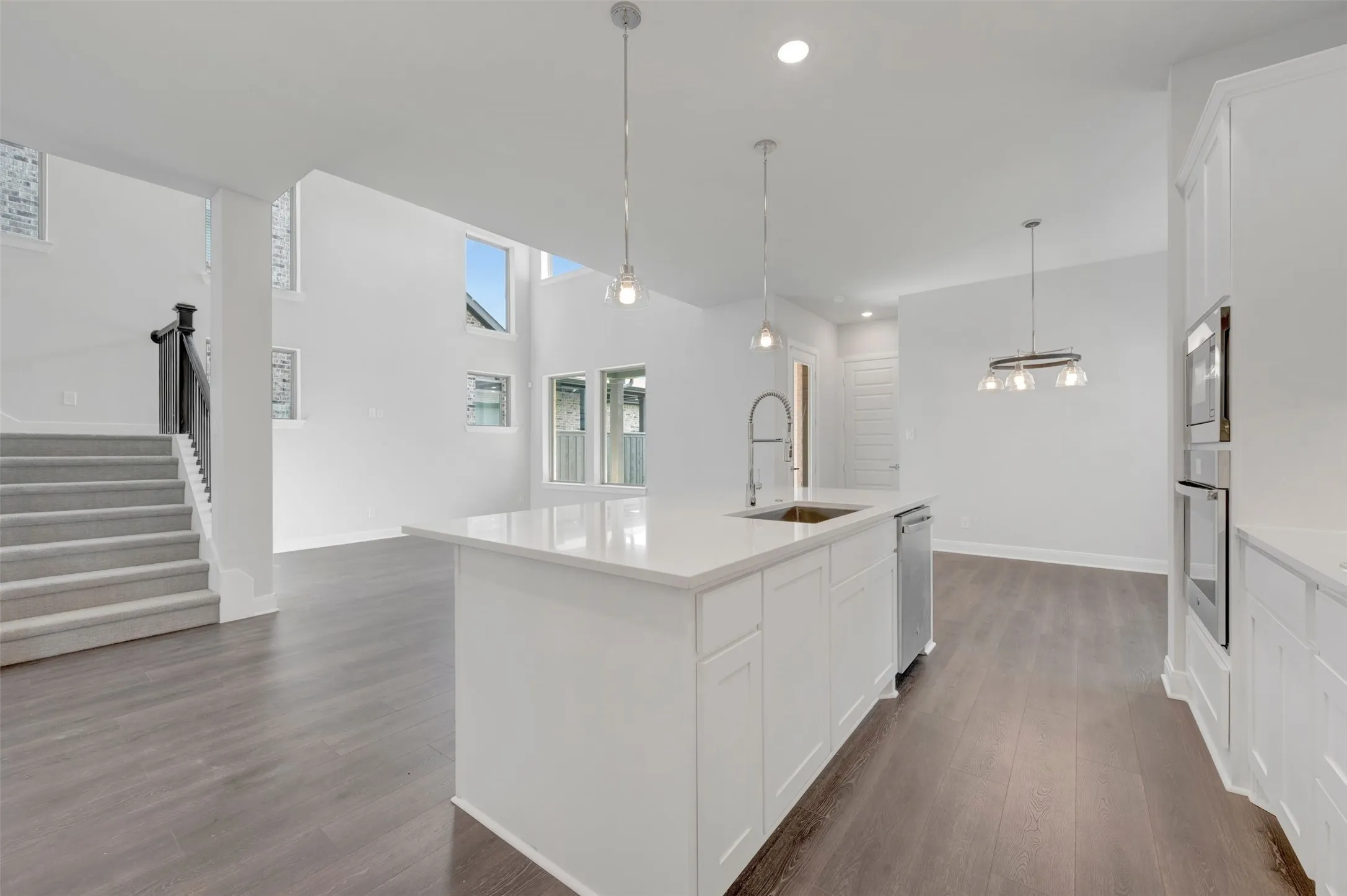 Open-concept living space featuring a central kitchen island with a built-in sink and dishwasher, white cabinetry, and light countertops