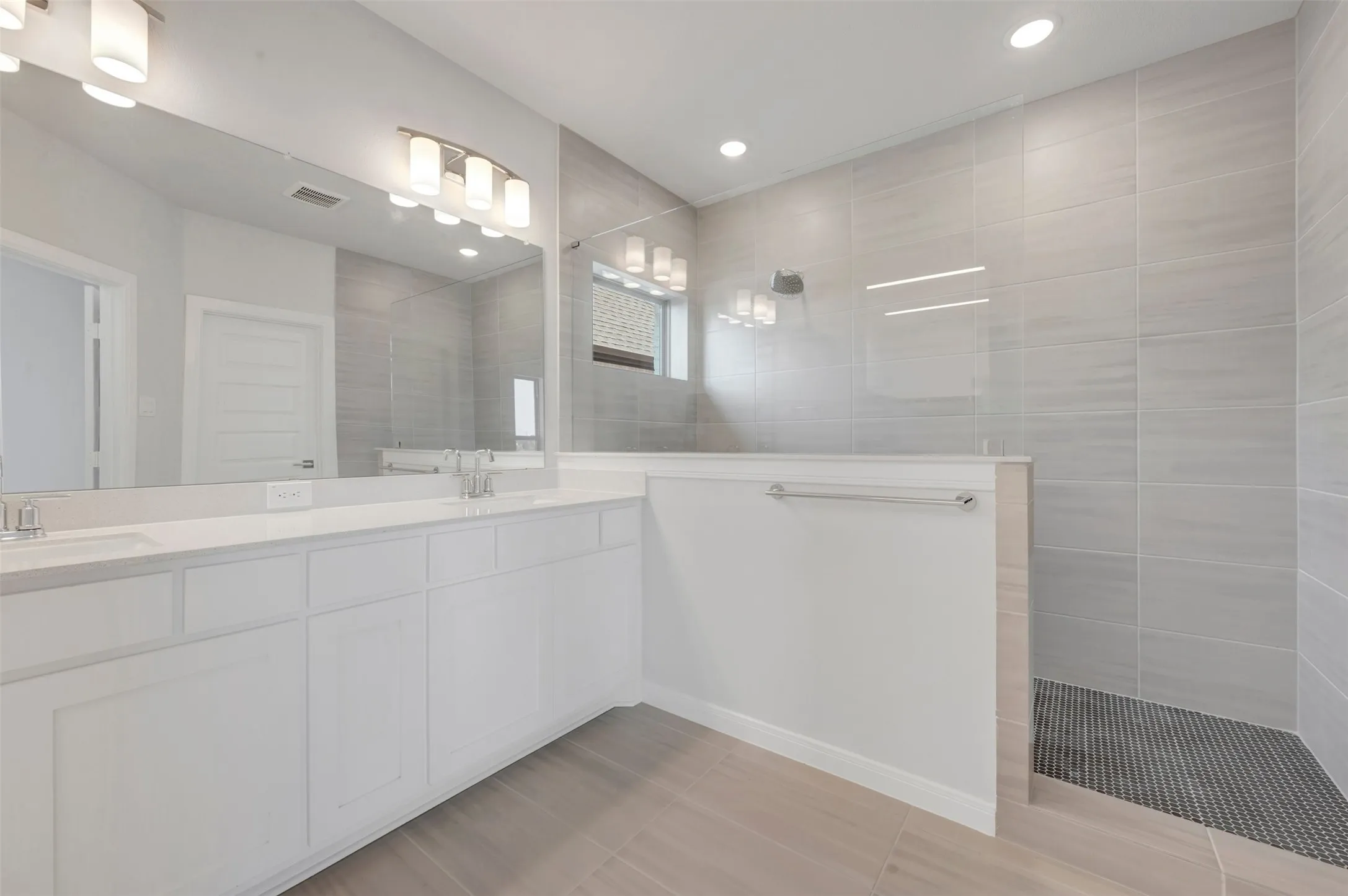 Contemporary bathroom featuring a dual vanity with white cabinetry and light-toned countertops