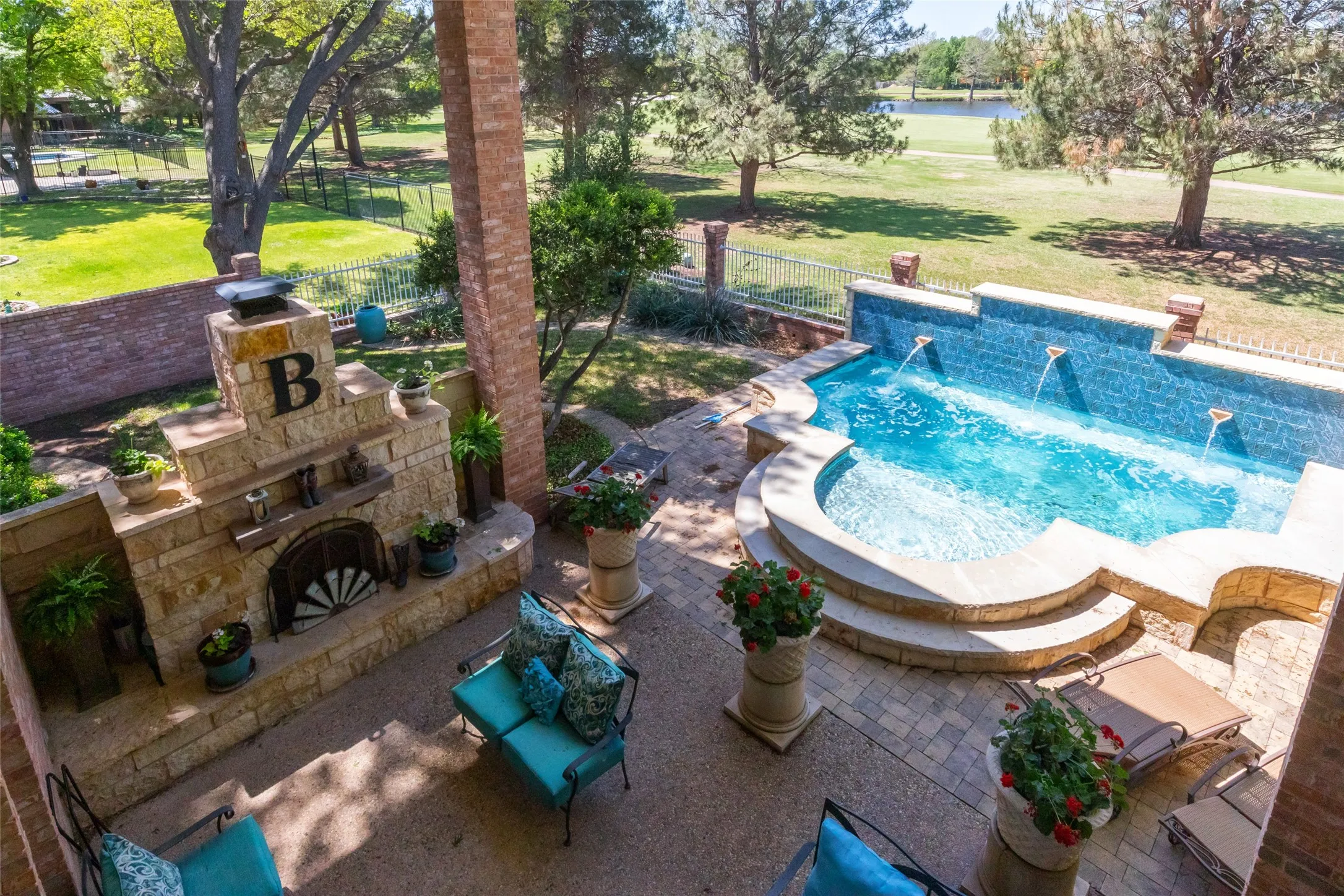 Outdoor living space with fireplace and spool with water feature.  Views of pond on the golf course.