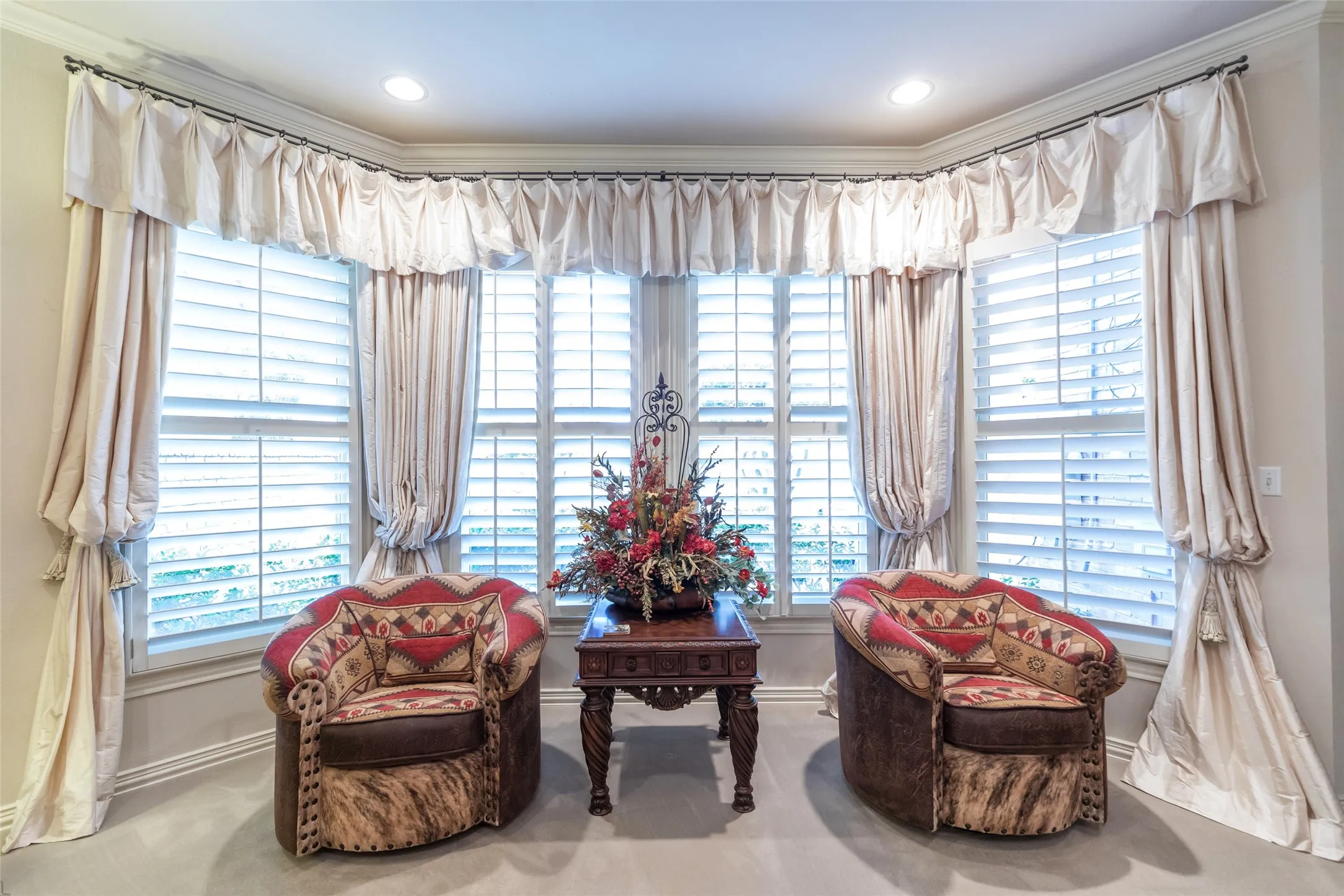 Bay window with plantation shutters and custom silk draperies in master bedroom.