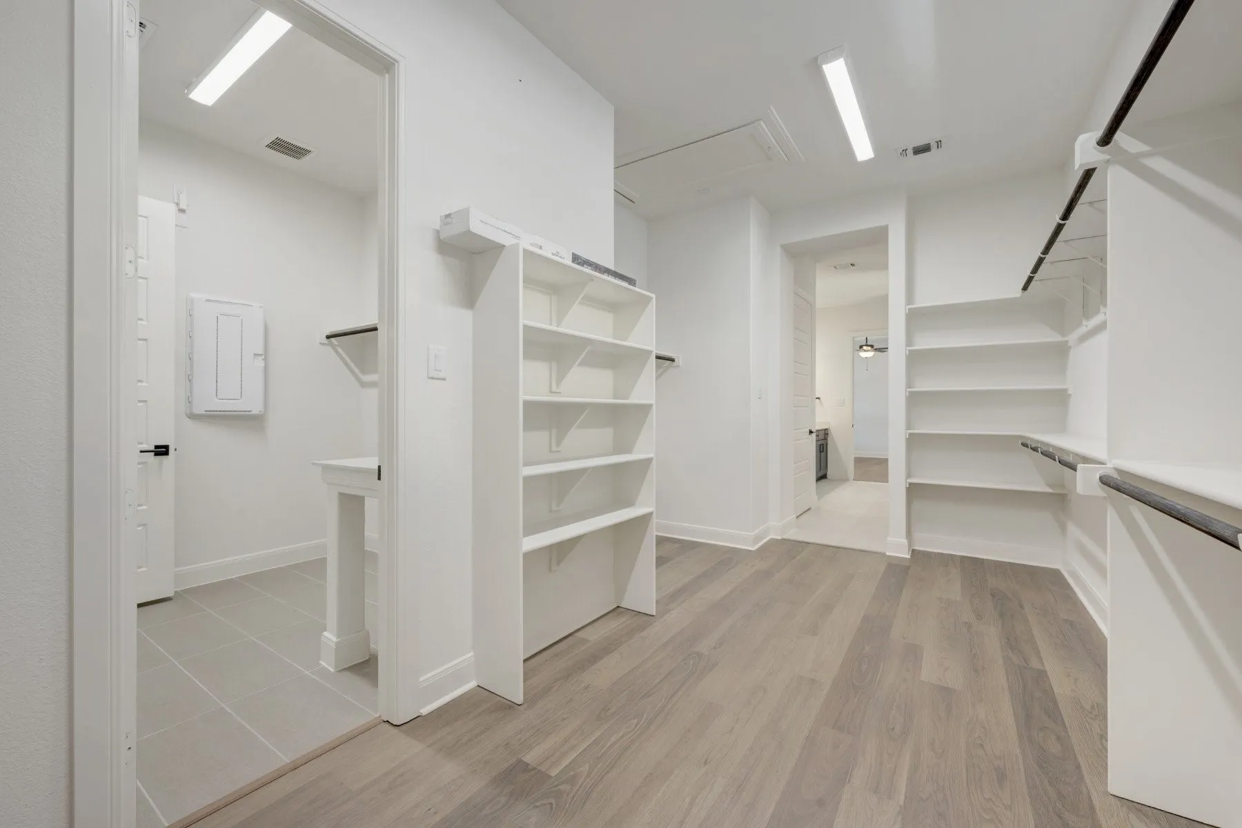 Spacious walk-in closet with wood-finish flooring, built-in shelving, and hanging rods