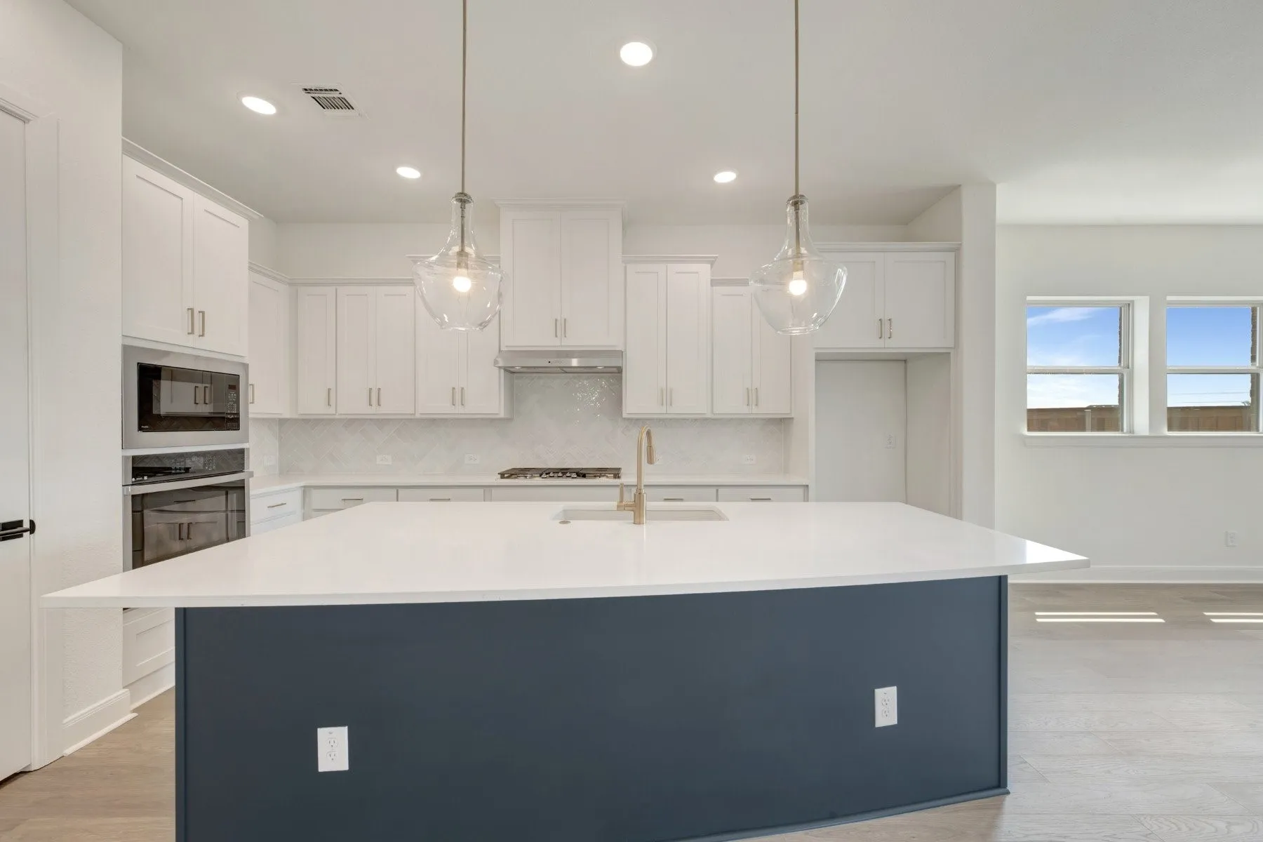 Kitchen featuring white cabinetry, a dark-toned island with a light-colored countertop, stainless steel appliances, and two pendant lights