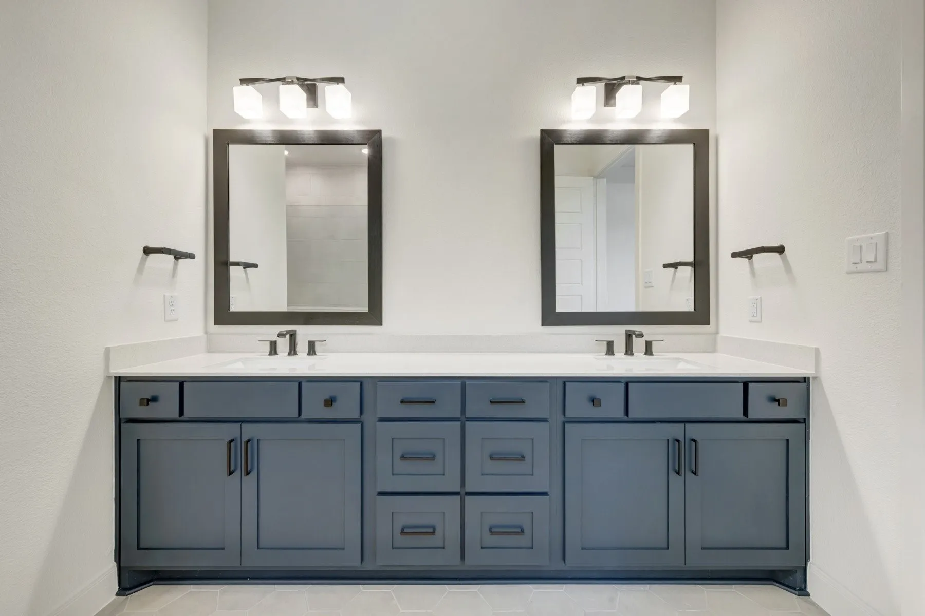 Dual vanity with gray shaker cabinetry, white countertop, individual rectangular mirrors, and individual three-light fixtures