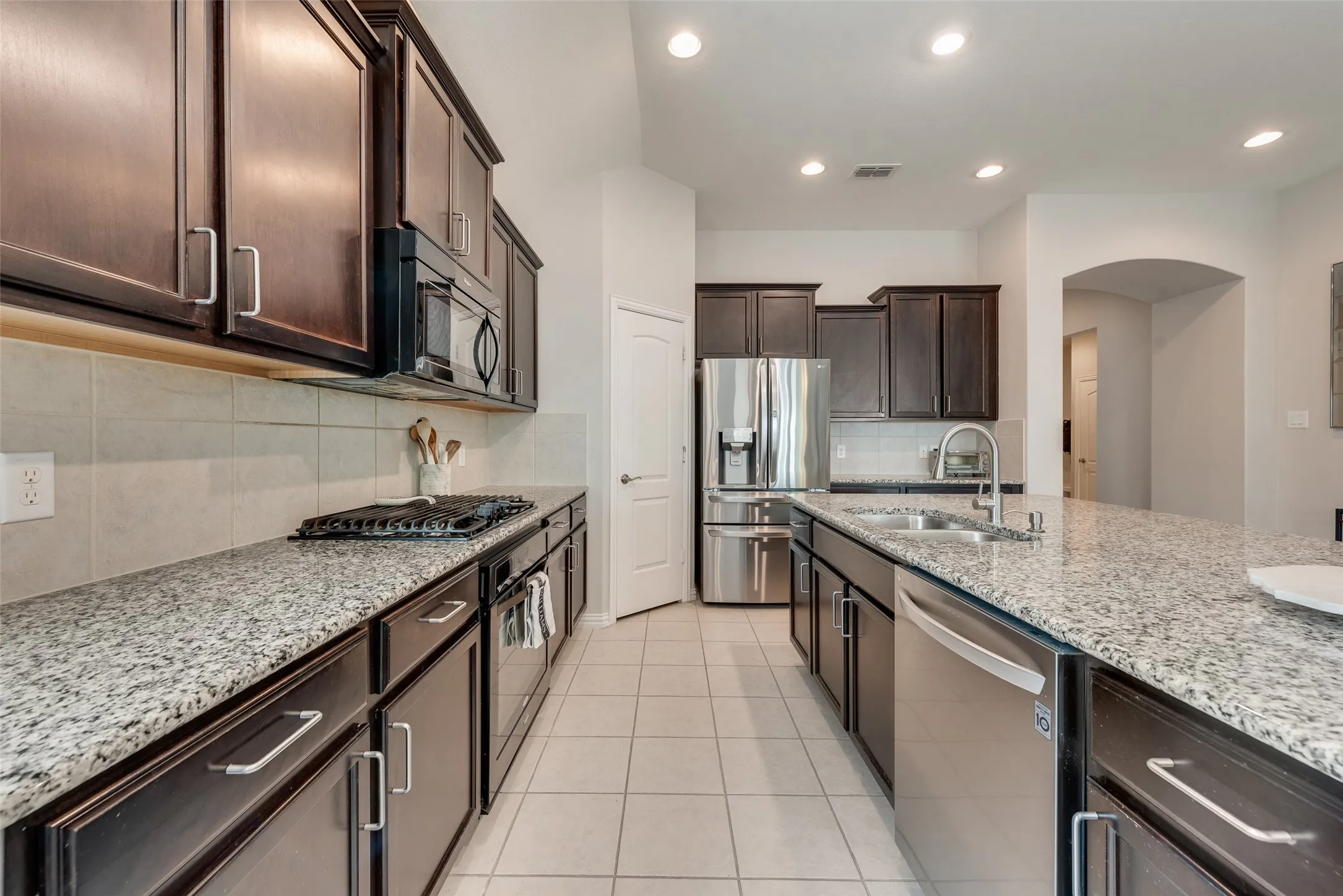 Spacious kitchen with oversized island, granite countertops, gas cooktop and walk-in pantry at 1432 Westview Ln in the Canyon Falls community in Northlake, TX