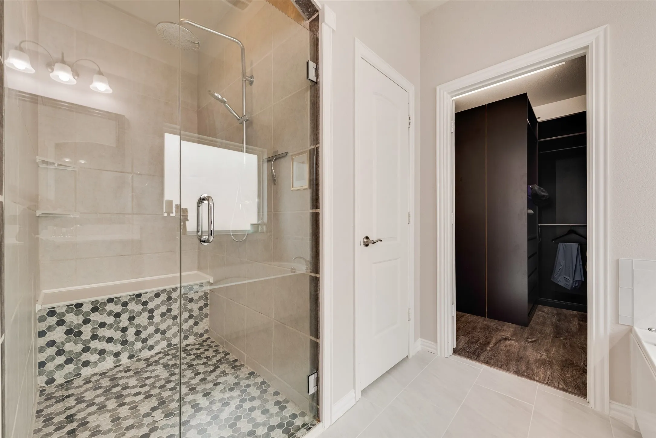 Primary bathroom with dual sinks, remodeled shower, ceramic tile floors and huge walk-in closet with modular system at 1432 Westview Ln in the Canyon Falls community in Northlake, TX
