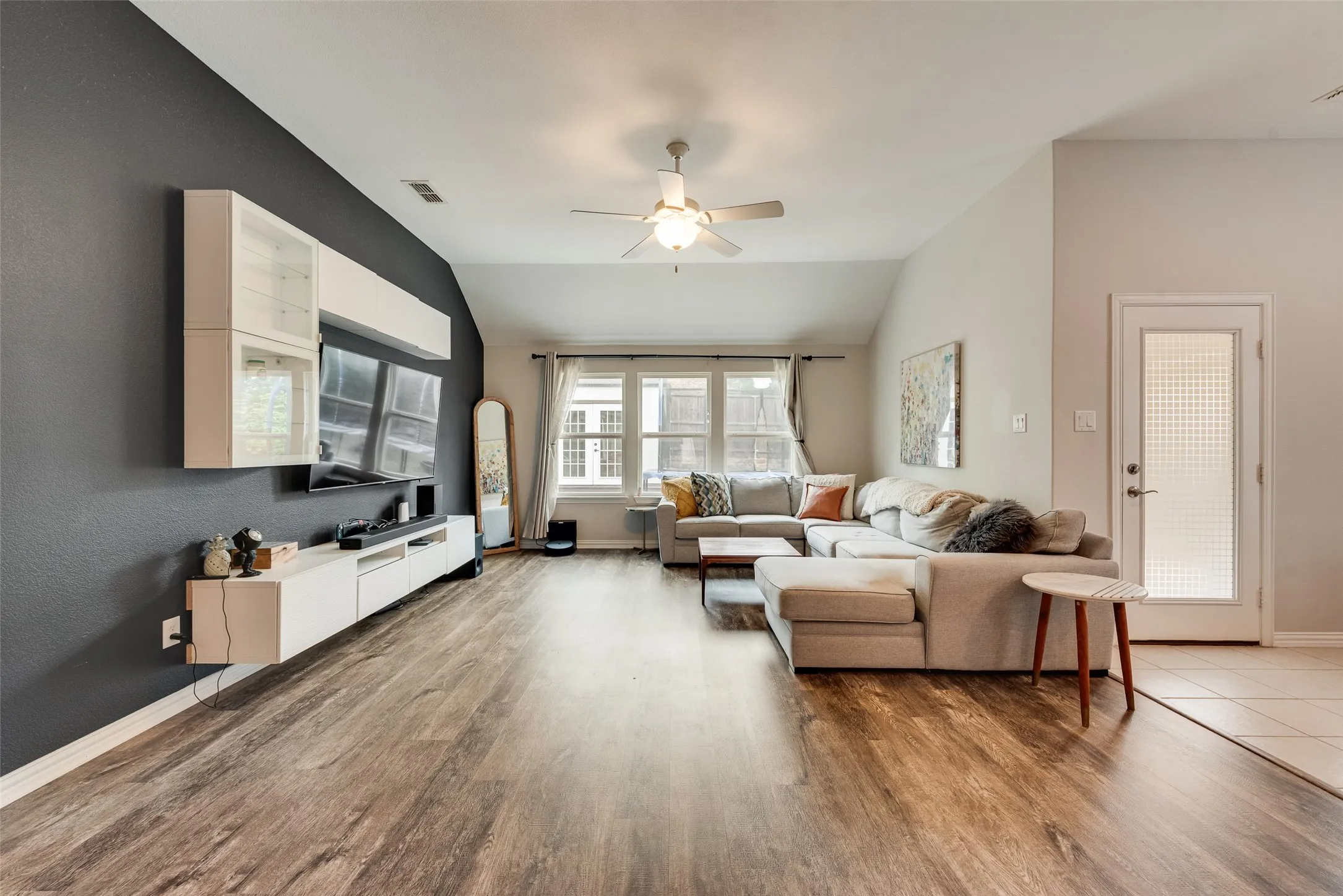 Spacious living room with new LVP flooring, accent wall, ceiling fan, and natural light from the large windows at 1432 Westview Ln in the Canyon Falls community in Northlake, TX