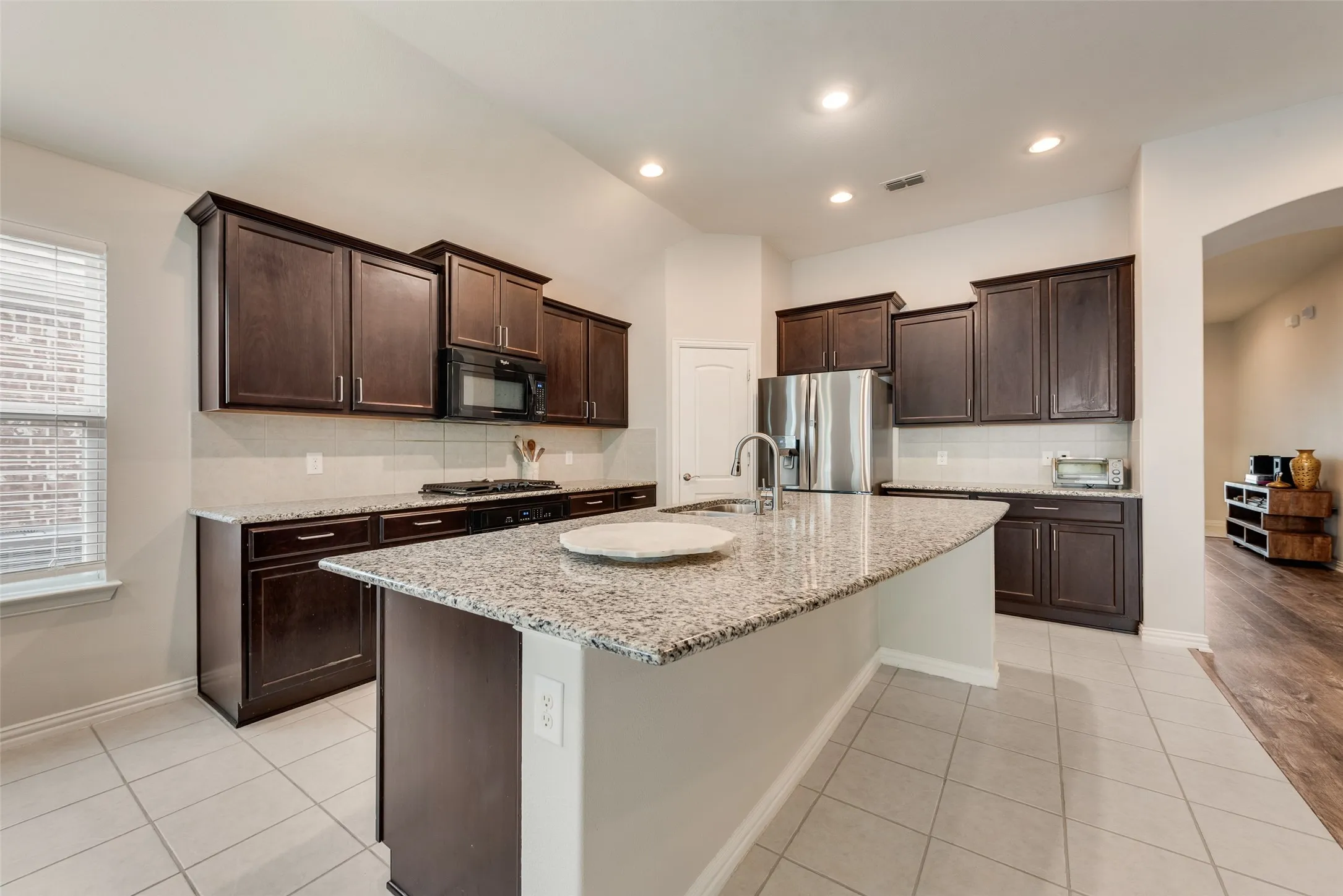 Spacious kitchen with oversized island, granite countertops, gas cooktop and walk-in pantry at 1432 Westview Ln in the Canyon Falls community in Northlake, TX