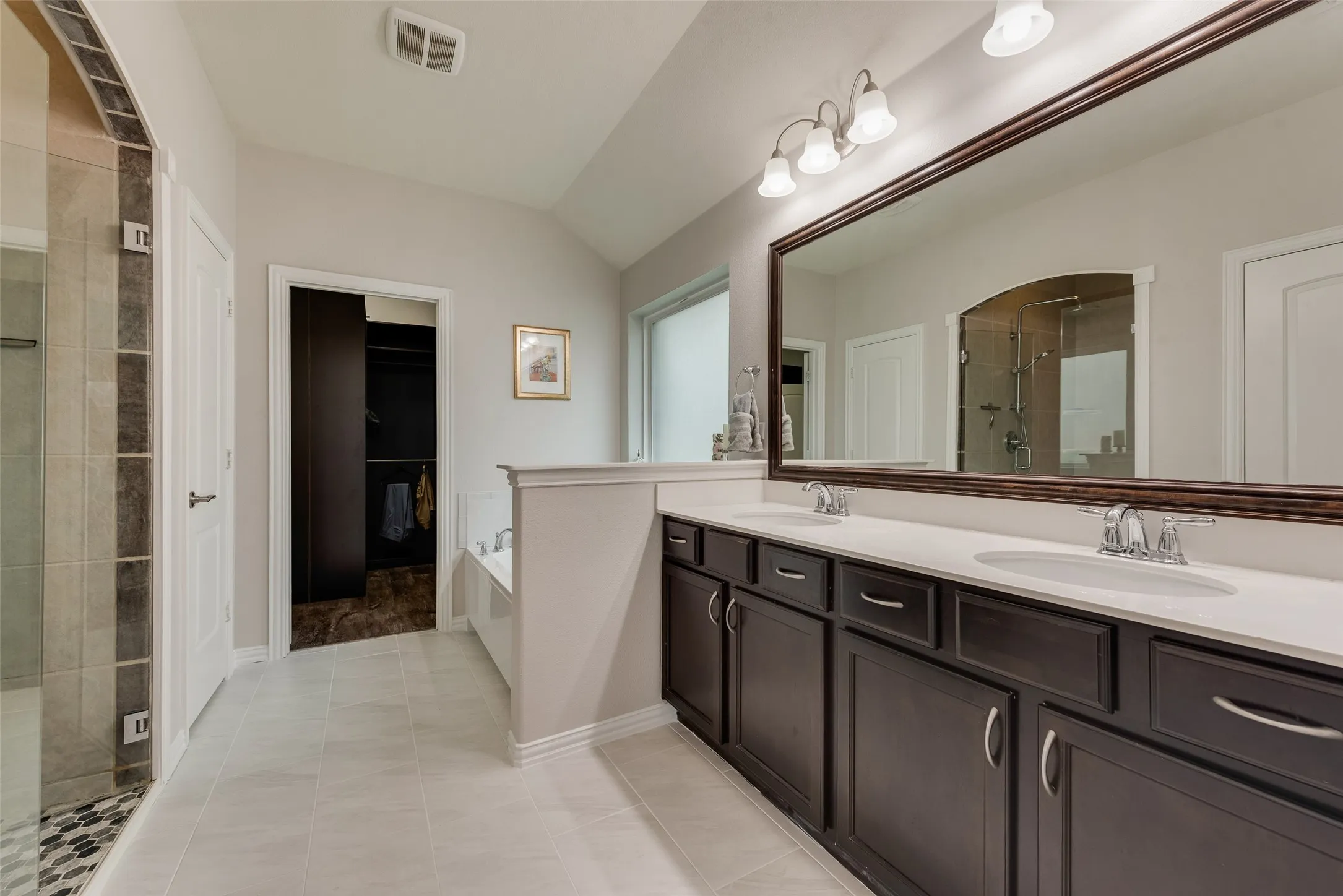 Primary bathroom with dual sinks, remodeled shower, ceramic tile floors and huge walk-in closet with modular system at 1432 Westview Ln in the Canyon Falls community in Northlake, TX