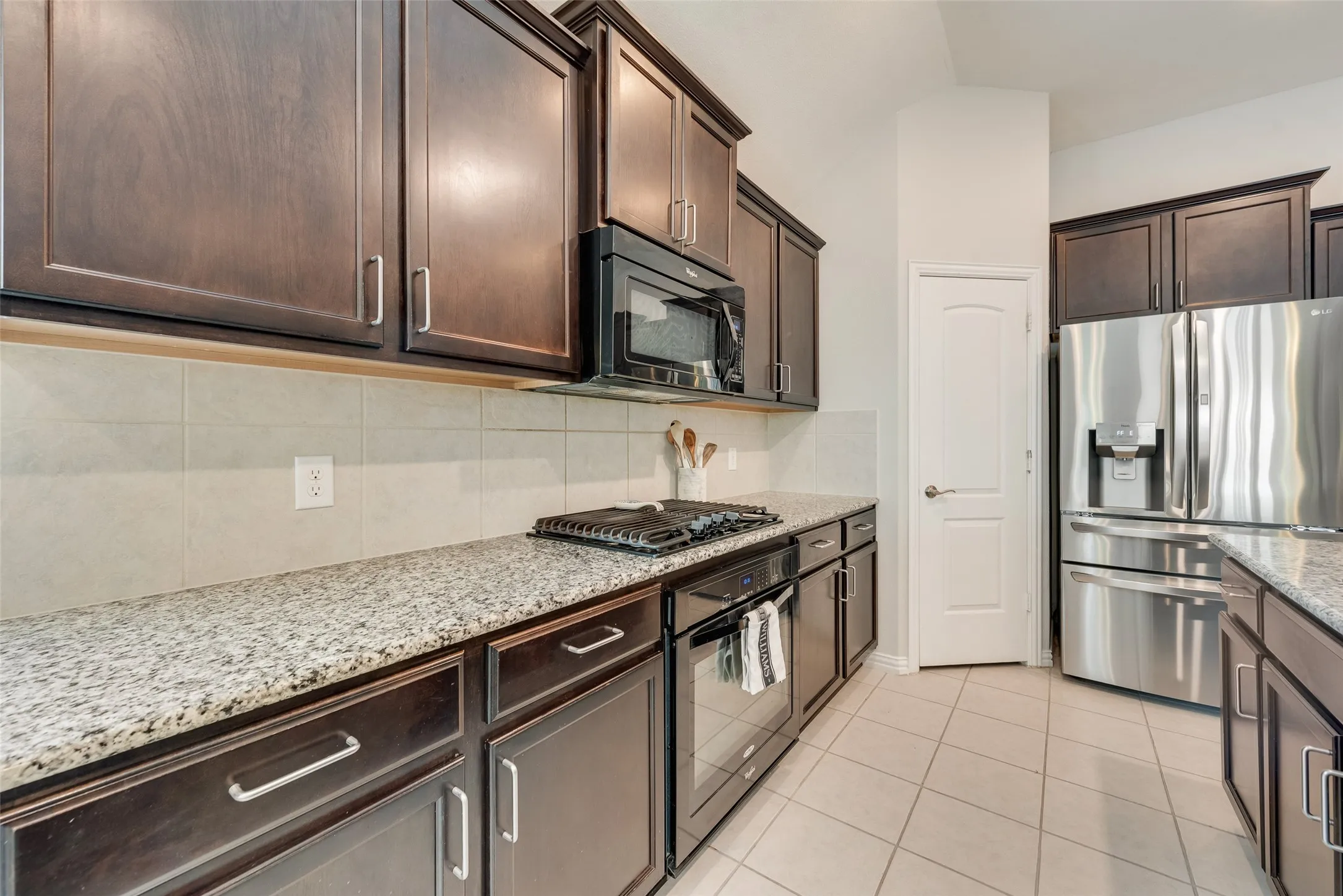 Spacious kitchen with oversized island, granite countertops, gas cooktop and walk-in pantry at 1432 Westview Ln in the Canyon Falls community in Northlake, TX