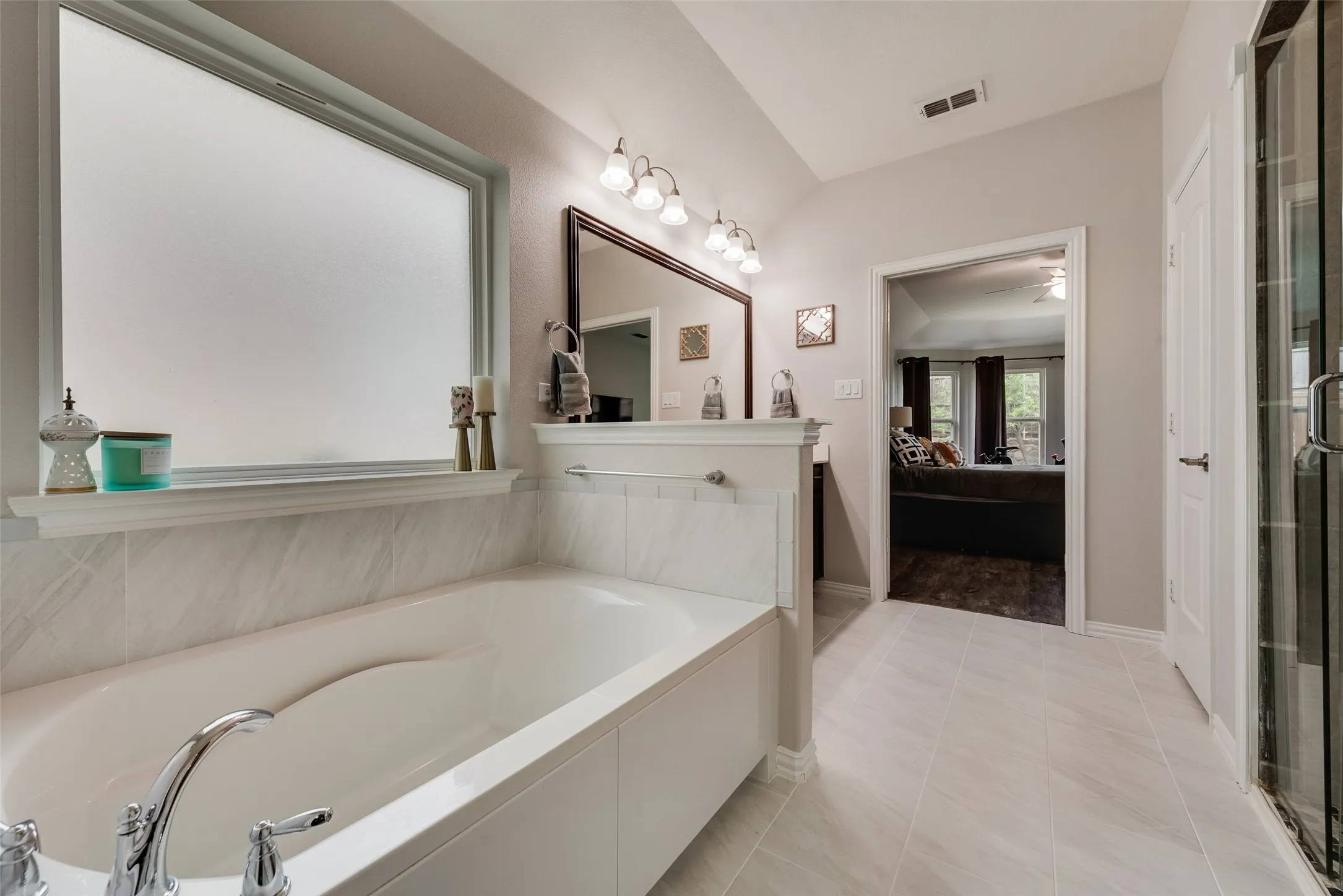 Primary bathroom with dual sinks, remodeled shower, ceramic tile floors and huge walk-in closet with modular system at 1432 Westview Ln in the Canyon Falls community in Northlake, TX