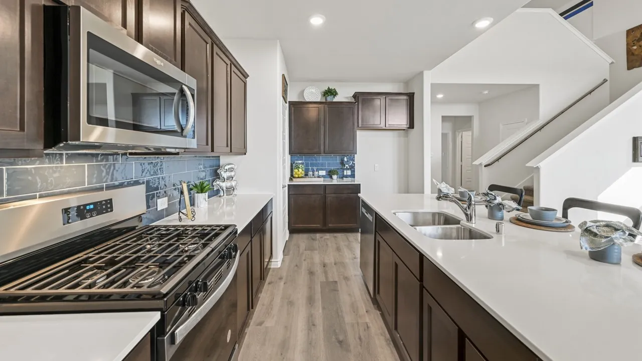 Modern kitchen featuring dark wood cabinetry, stainless steel appliances, light countertops, a subway tile backsplash, and wood-finish flooring