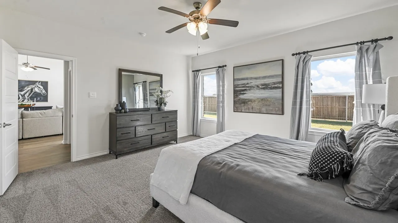 Spacious room featuring light-colored walls, carpeted flooring, and a ceiling fan with integrated lighting
