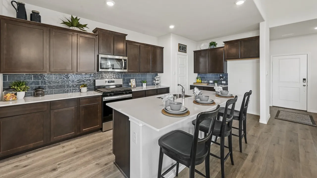 Well-appointed kitchen featuring dark wood cabinetry, stainless steel appliances, a subway tile backsplash, light-toned countertops, and wood-finish flooring