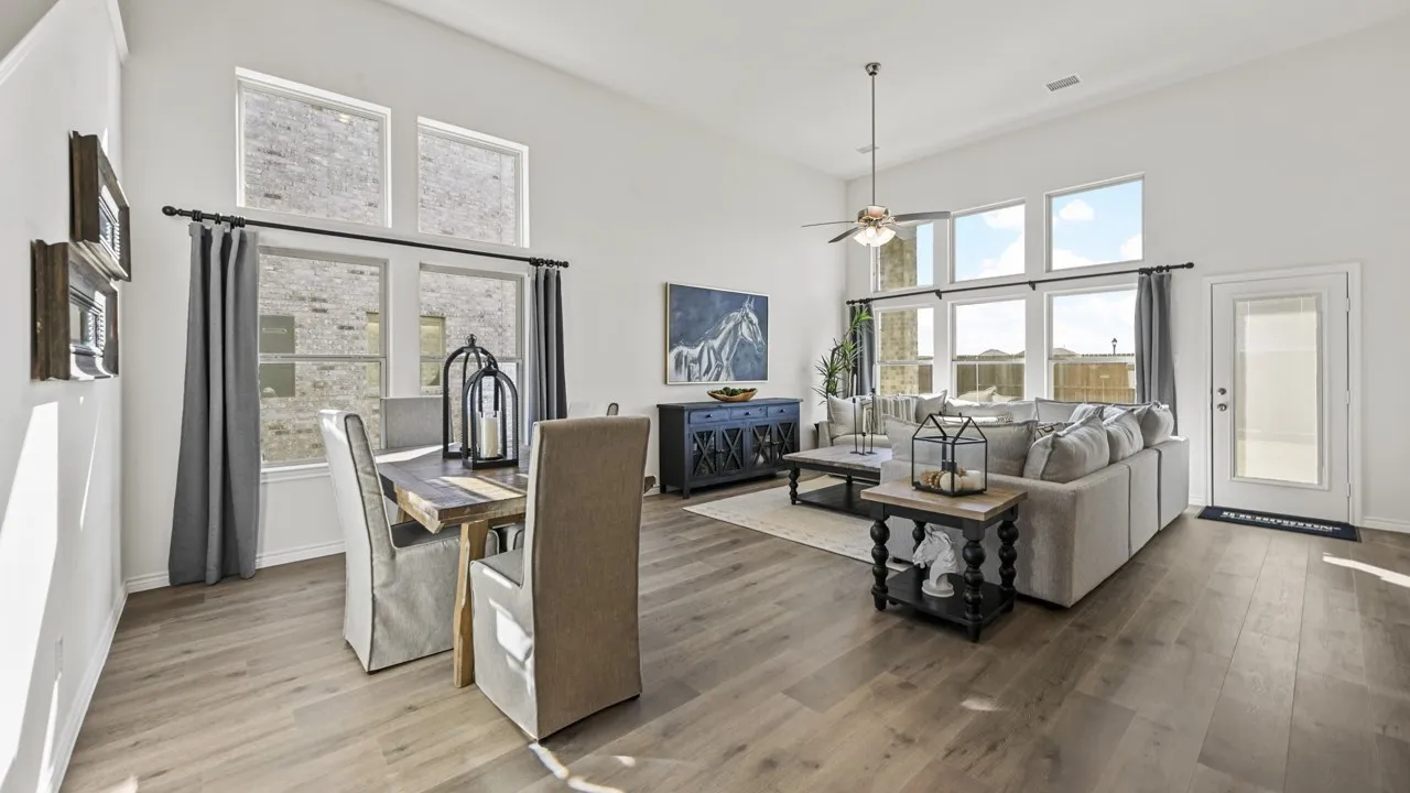 Open-concept living space featuring high vaulted ceilings, extensive window banks, and wood-finish flooring