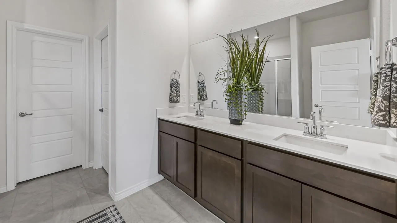 Dual vanity with white countertops, undermount sinks, chrome faucets, and dark wood-finish cabinetry