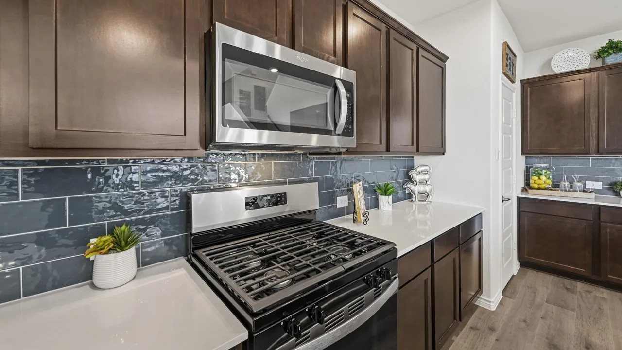 Kitchen featuring dark wood cabinetry, white countertops, and a blue subway tile backsplash