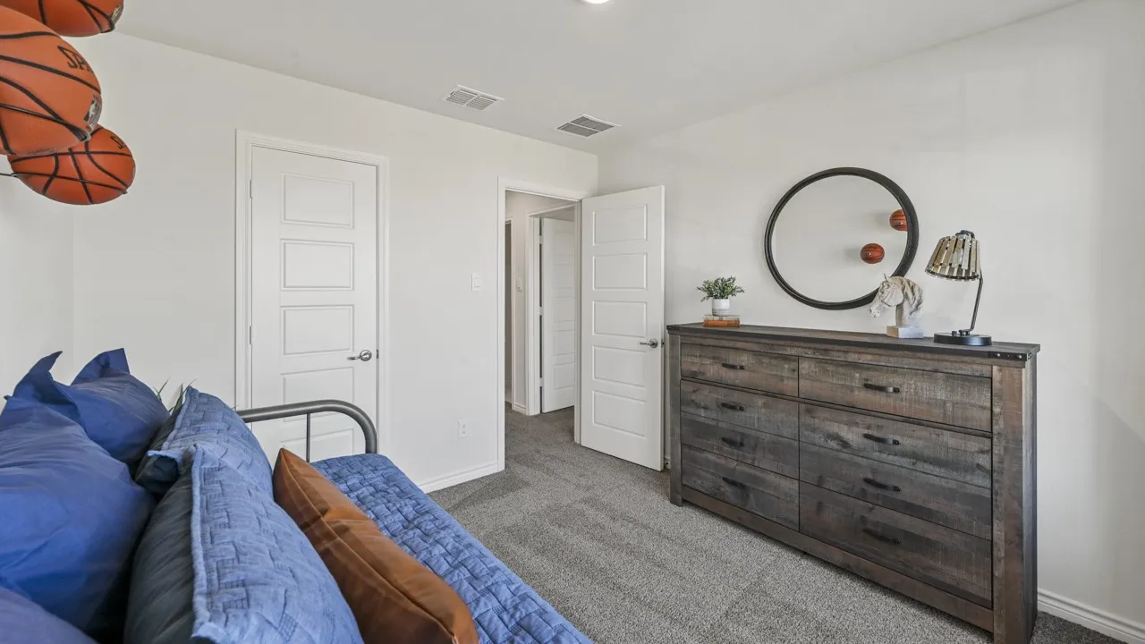 Spacious room featuring light gray carpet, multiple white interior doors with contemporary paneling, and a rustic wood-finish dresser with dark hardware