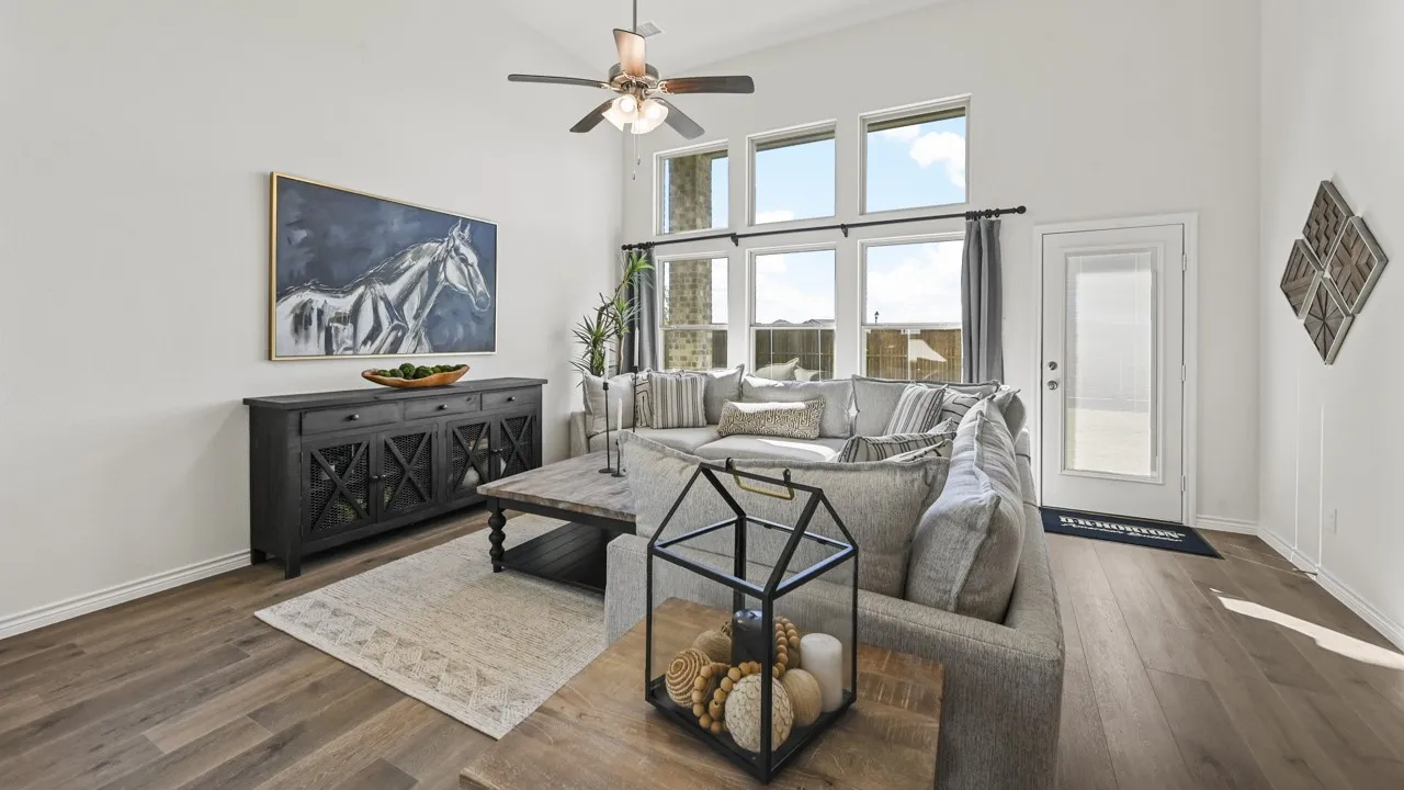 Spacious living area featuring high ceilings, wood-finish flooring, and multiple windows allowing abundant natural light