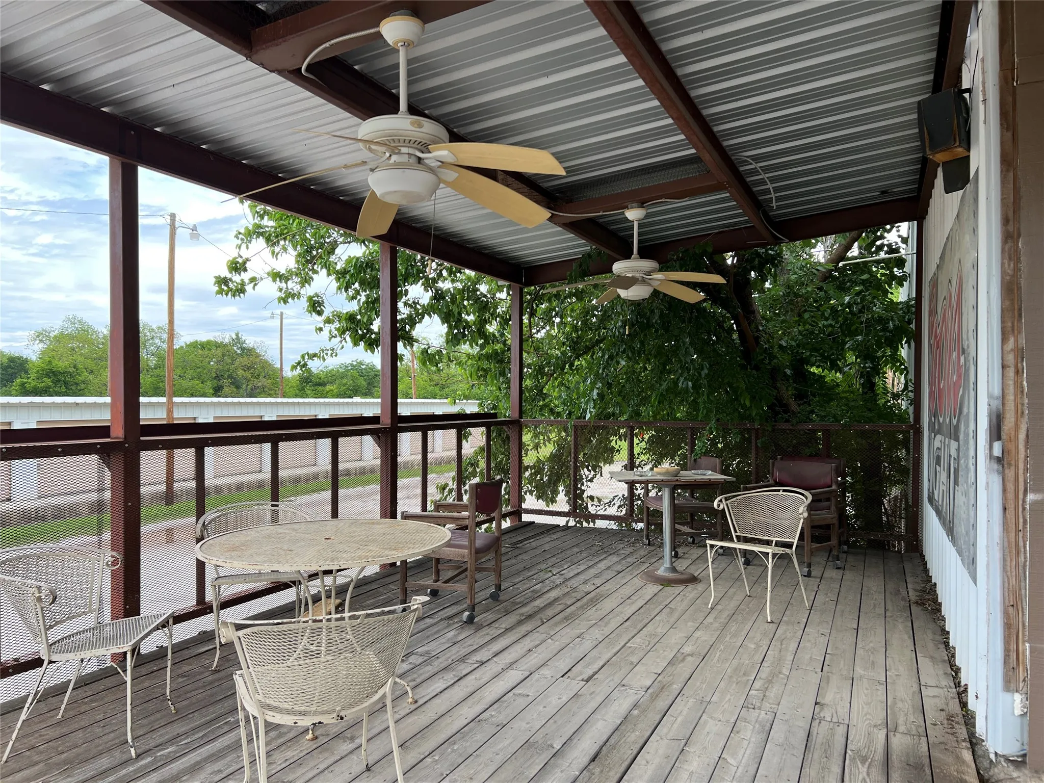 Covered outdoor patio featuring exposed wood flooring and a corrugated metal roof
