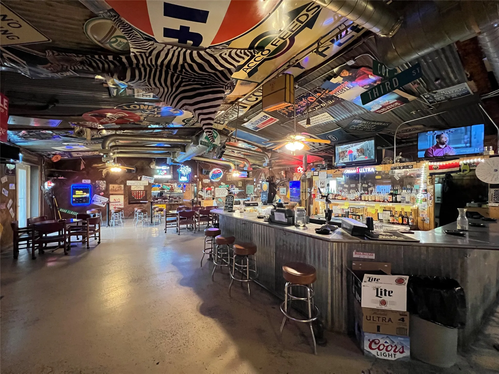 Full-service bar area featuring a corrugated metal bar, multiple built-in televisions, and exposed ductwork