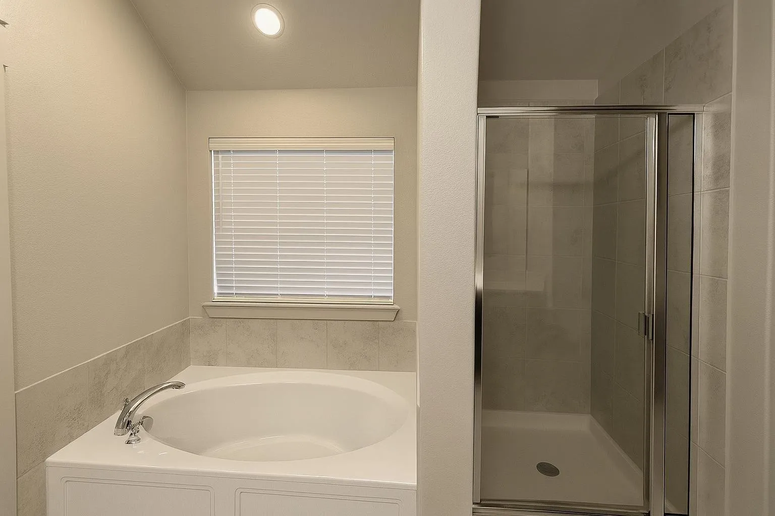 Bathroom featuring a built-in soaking tub with chrome fixtures, a window with horizontal blinds, and an adjacent enclosed shower with a glass door and tiled walls