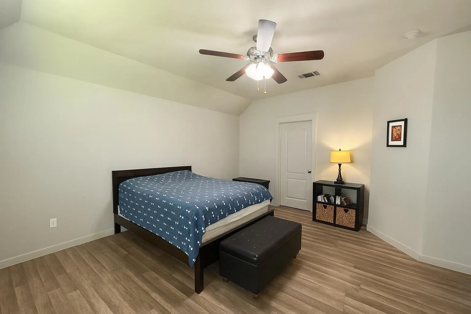 Room featuring wood-finish flooring, a vaulted ceiling, and a ceiling fan with integrated lighting