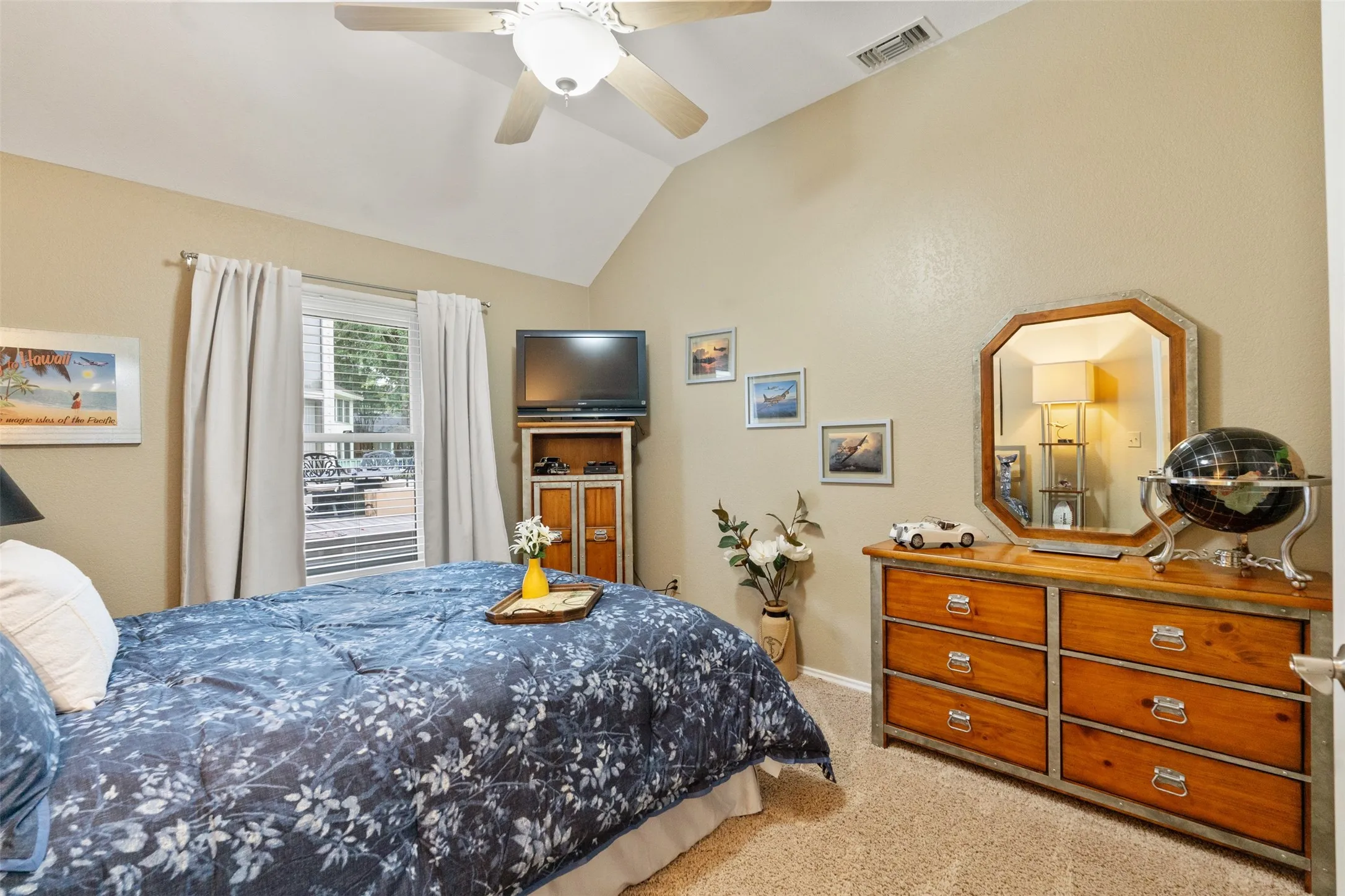 Sloped ceiling bedroom featuring a ceiling fan, window with exterior exposure, and neutral carpet flooring